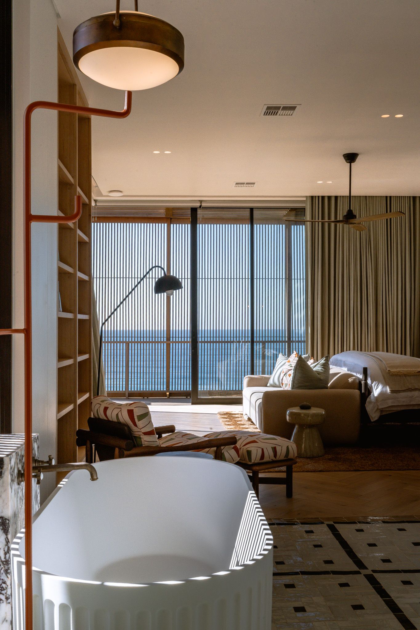 Modern oceanfront bedroom with floor-to-ceiling windows and contemporary lighting fixtures.
