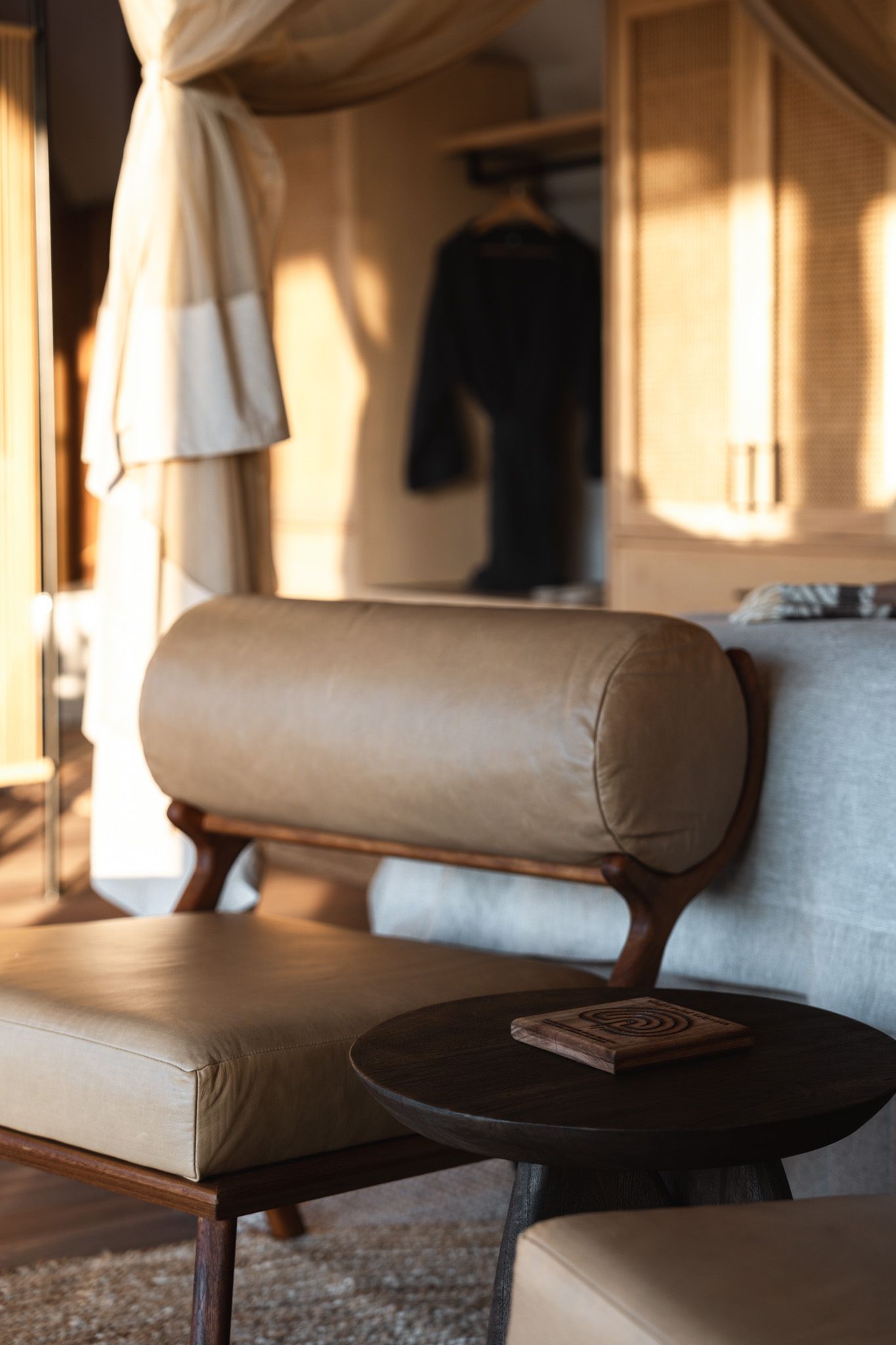 Tan leather lounge chair with round side table in sunlit corner of room.