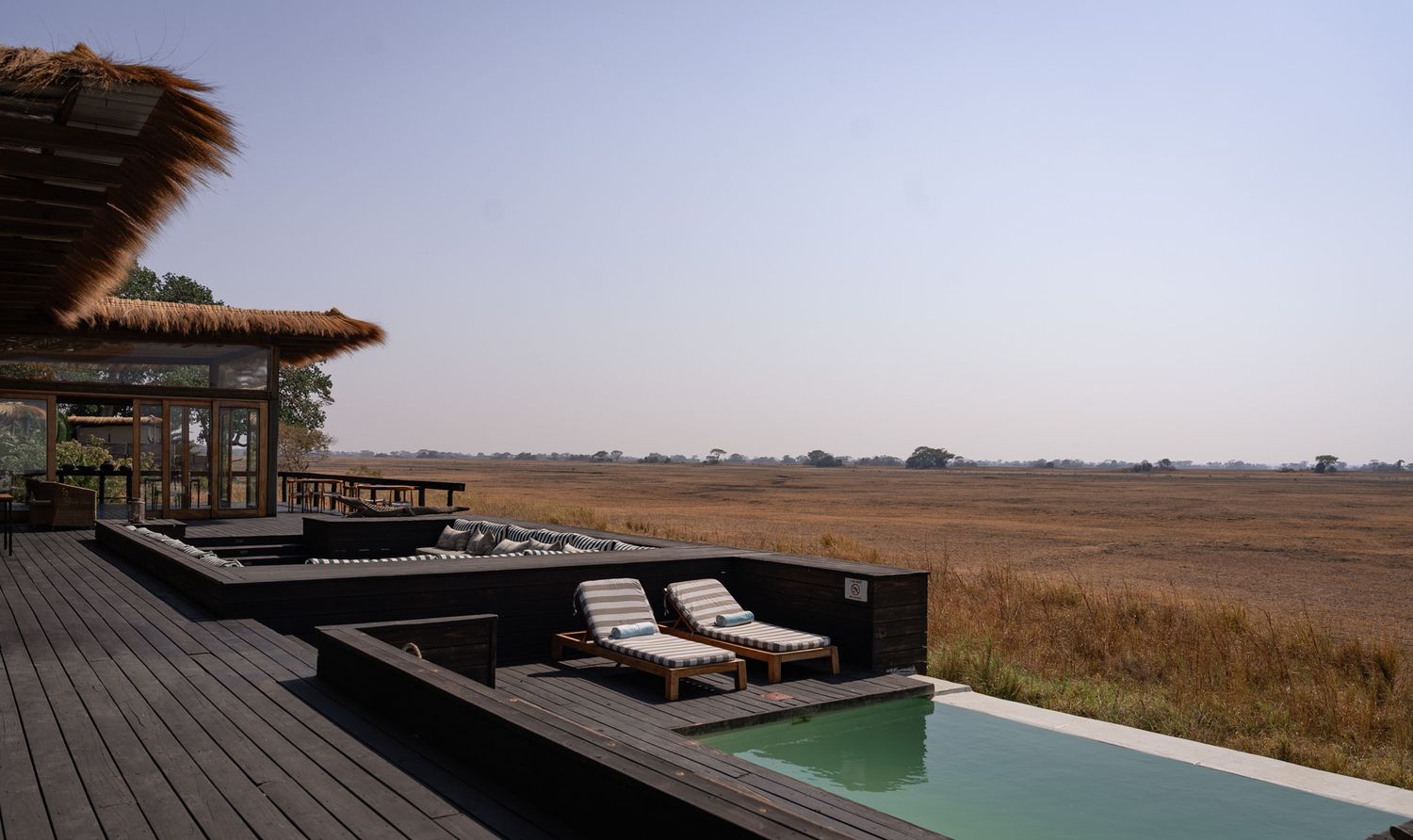 Modern safari lodge deck with infinity pool overlooking vast African savanna.