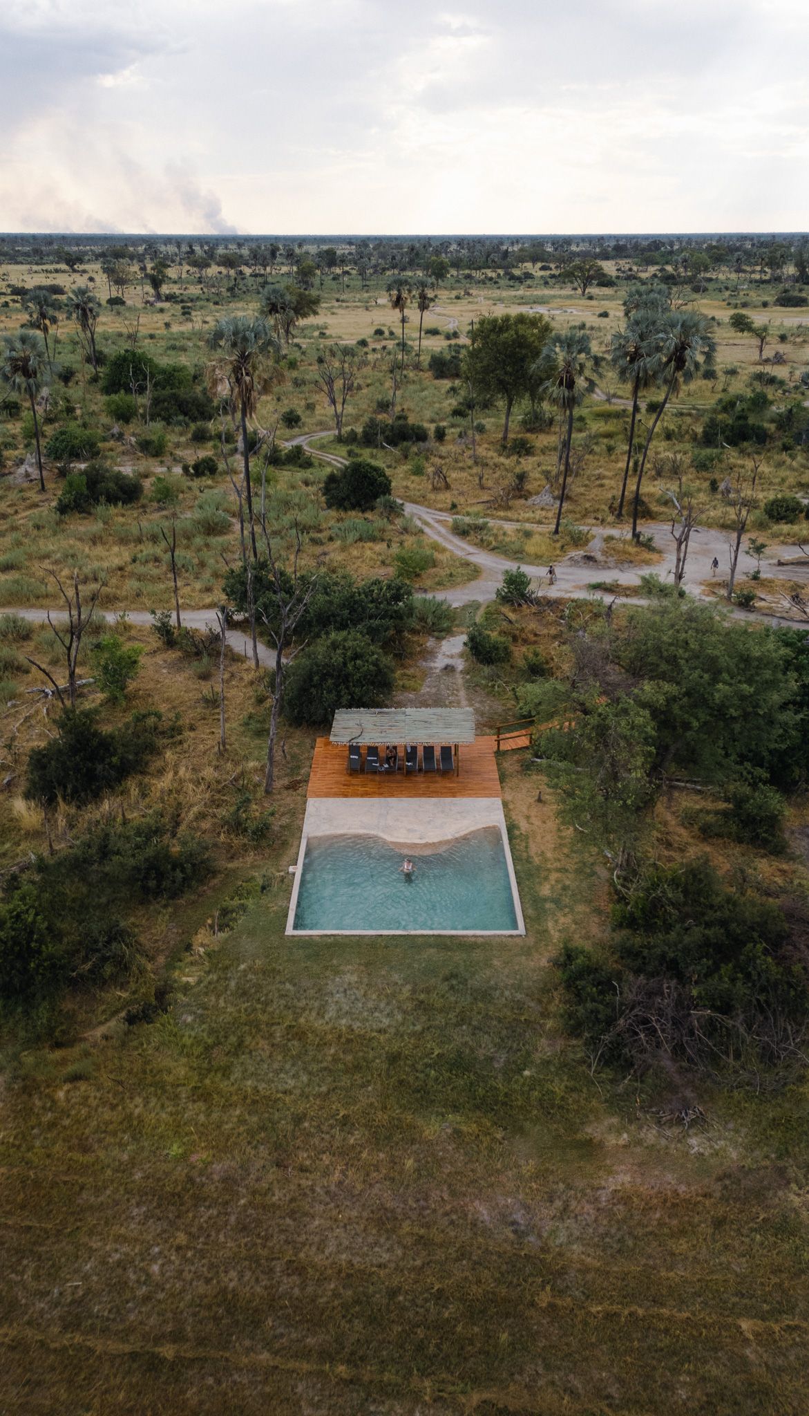 Aerial view of swimming pool and modern structure in remote grassland setting.