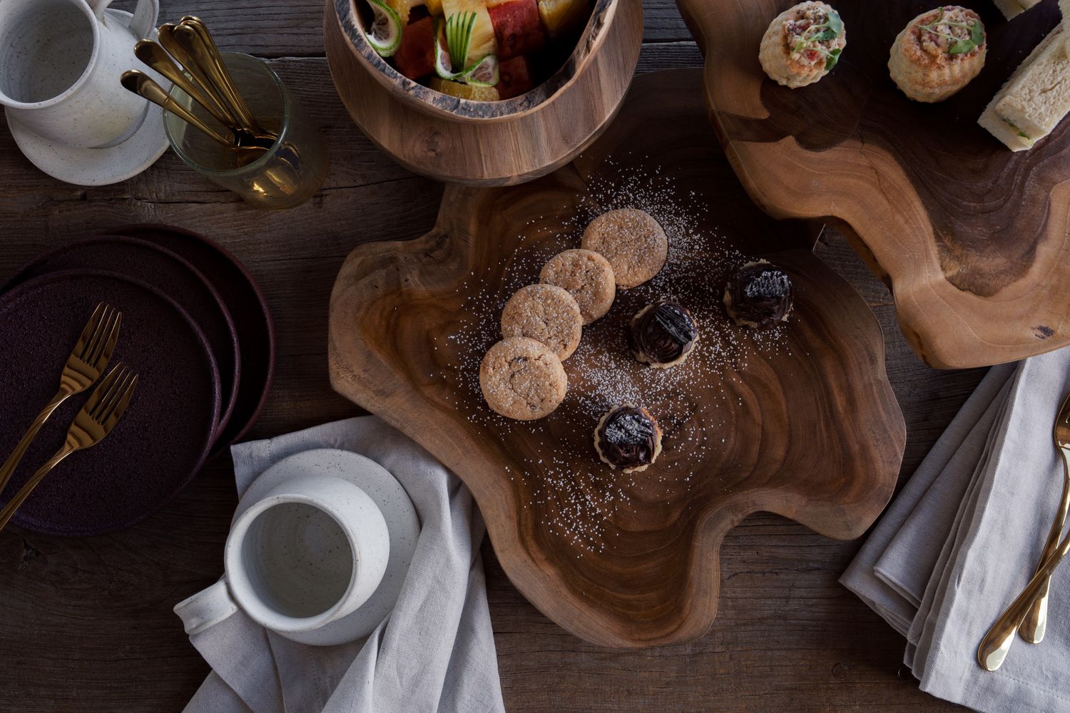 Overhead view of coffee service setup with wooden serving boards on dark table.