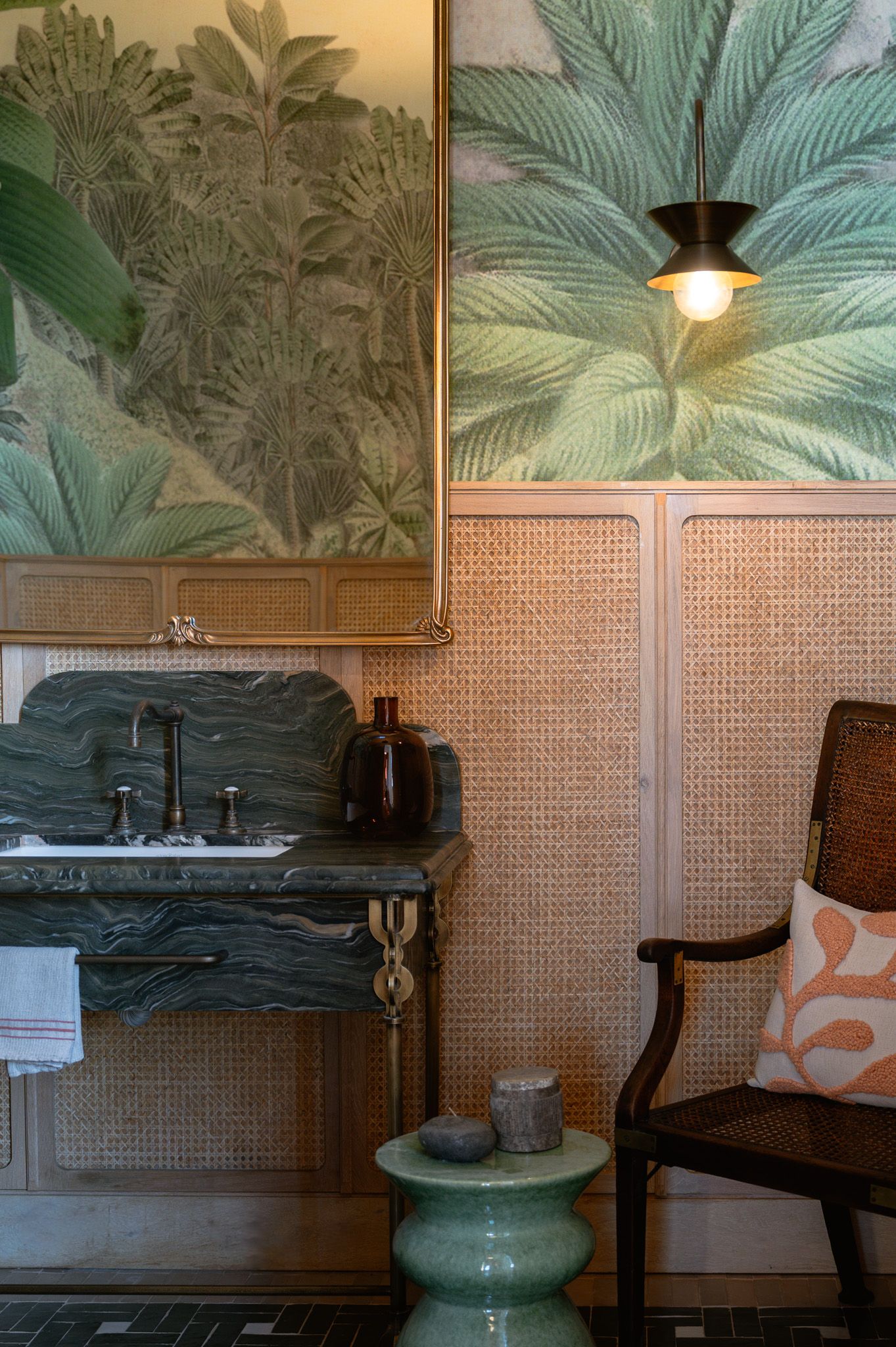 Tropical palm leaf wallpaper design above woven cane paneling and dark wooden furniture.