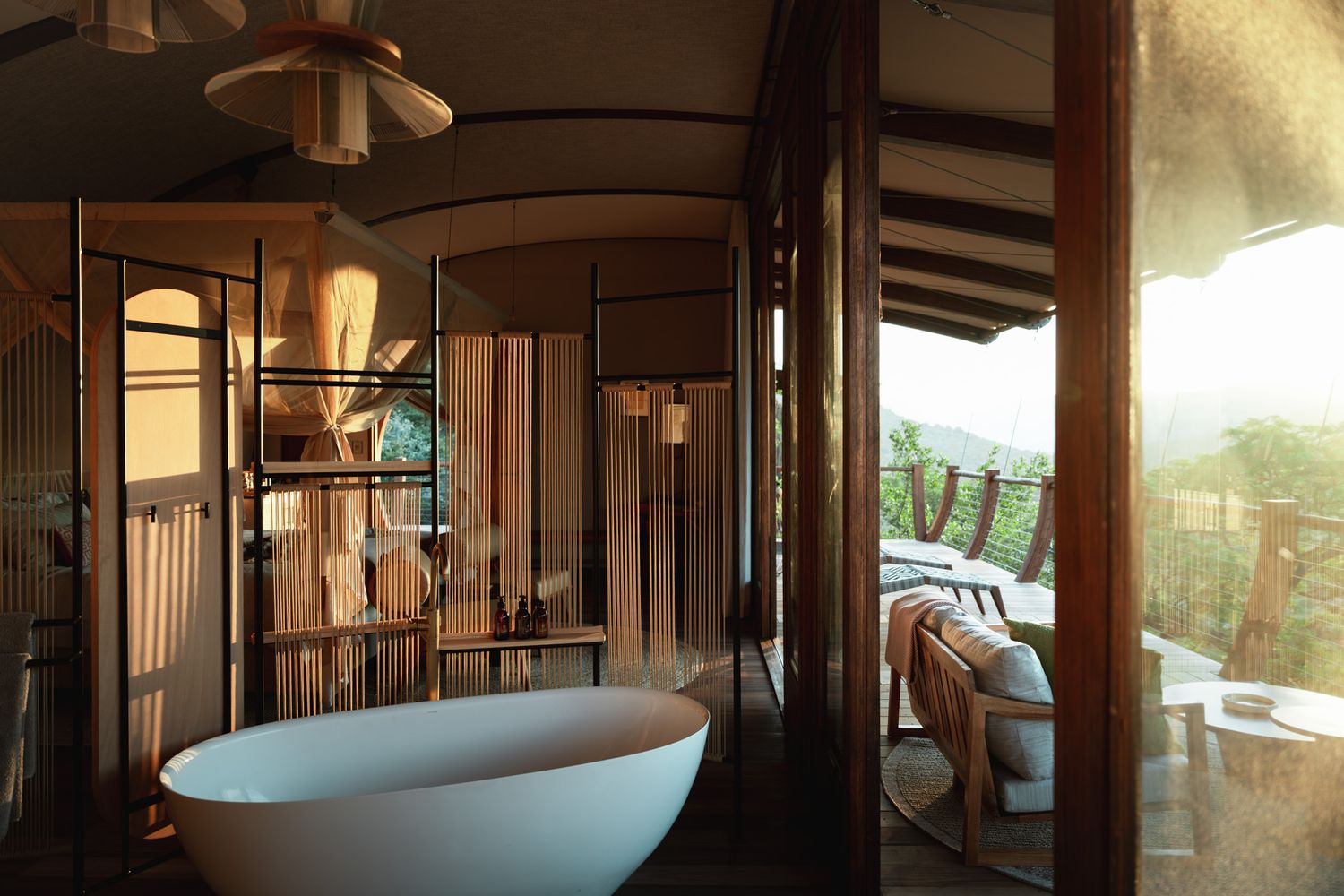 Luxury bathroom with freestanding tub and panoramic windows overlooking natural landscape.