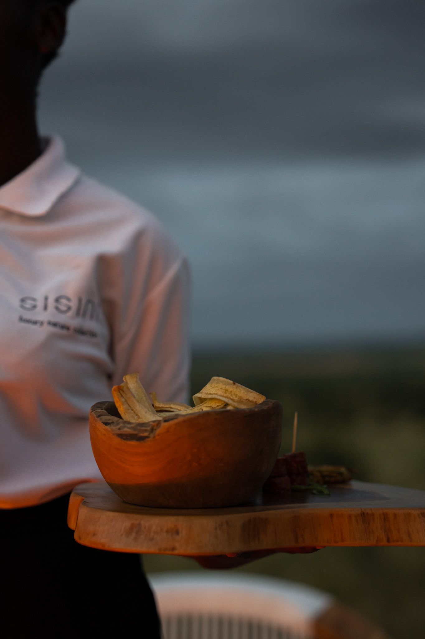 Wooden serving bowls illuminated by warm lighting in moody restaurant atmosphere.