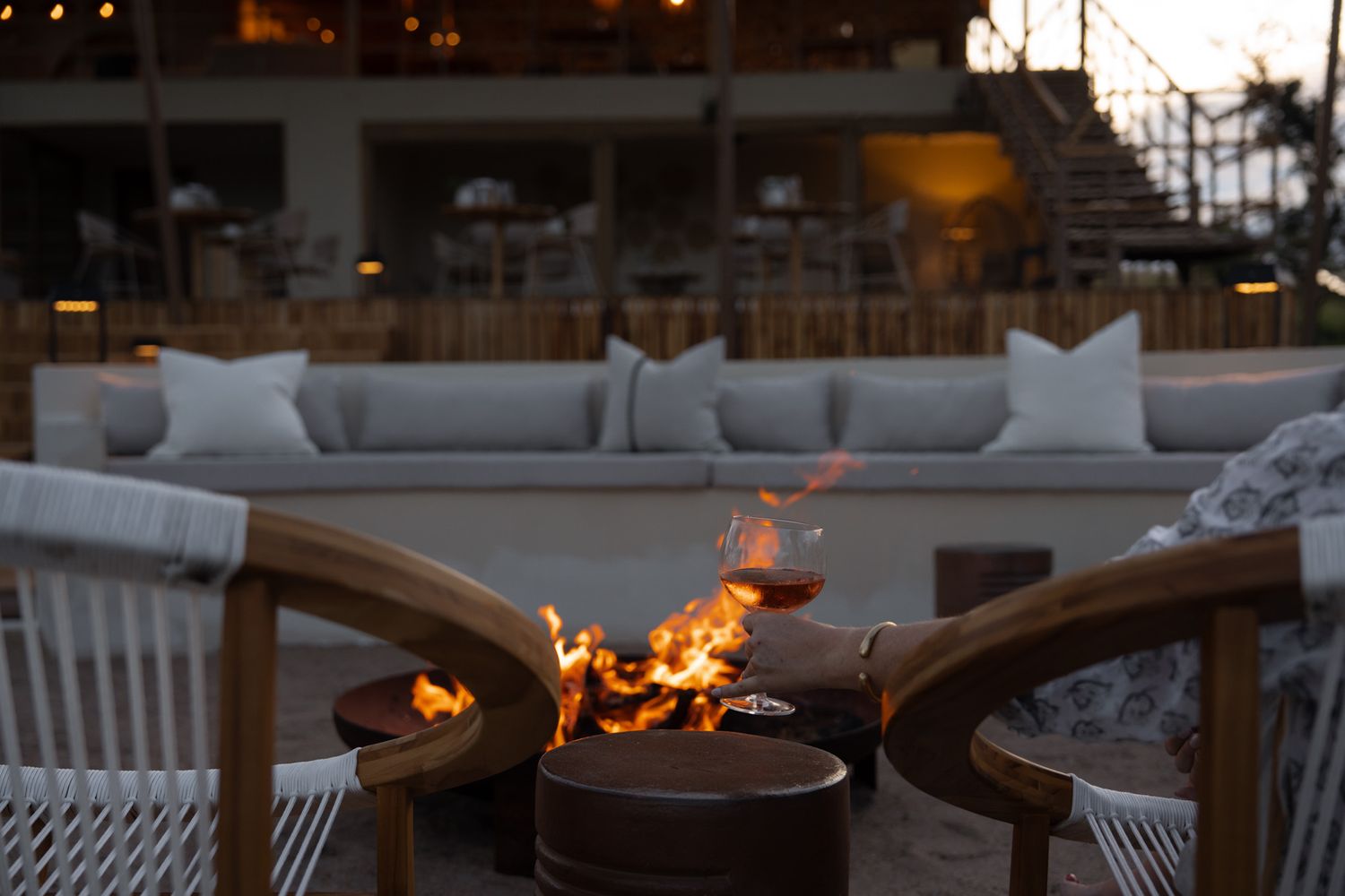 Modern outdoor seating area with blazing fire pit at dusk.