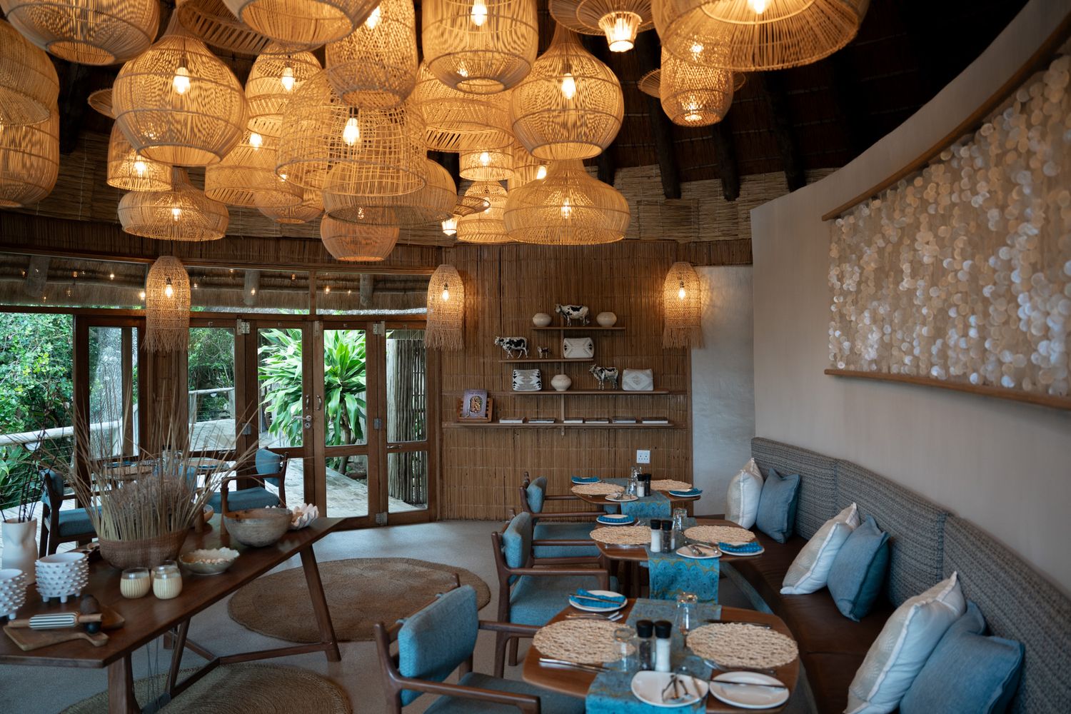Modern indoor dining area with hanging pendant lights and contemporary furnishings in warm earthy tones.