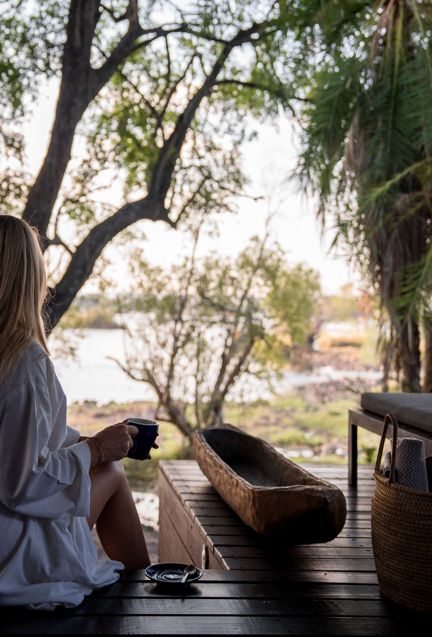 Peaceful morning scene with coffee and traditional wooden boat on lakeside deck.