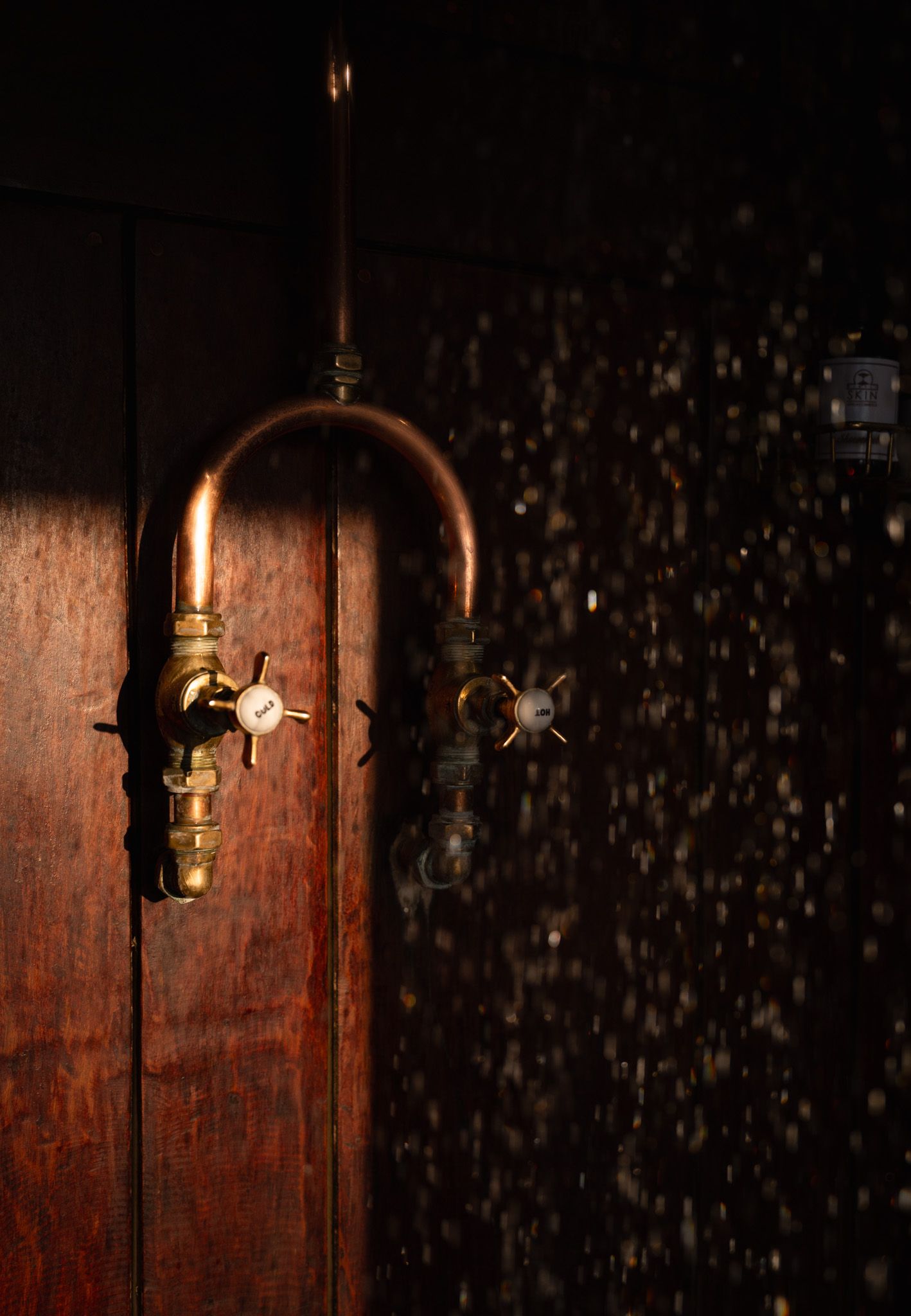 Vintage wooden cabinet detail with decorative metal hardware illuminated by dramatic lighting.