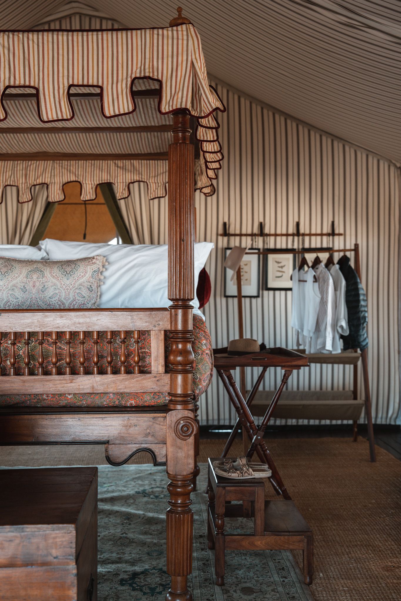 Rustic wooden four-poster bed with striped canopy in a vintage-styled bedroom.