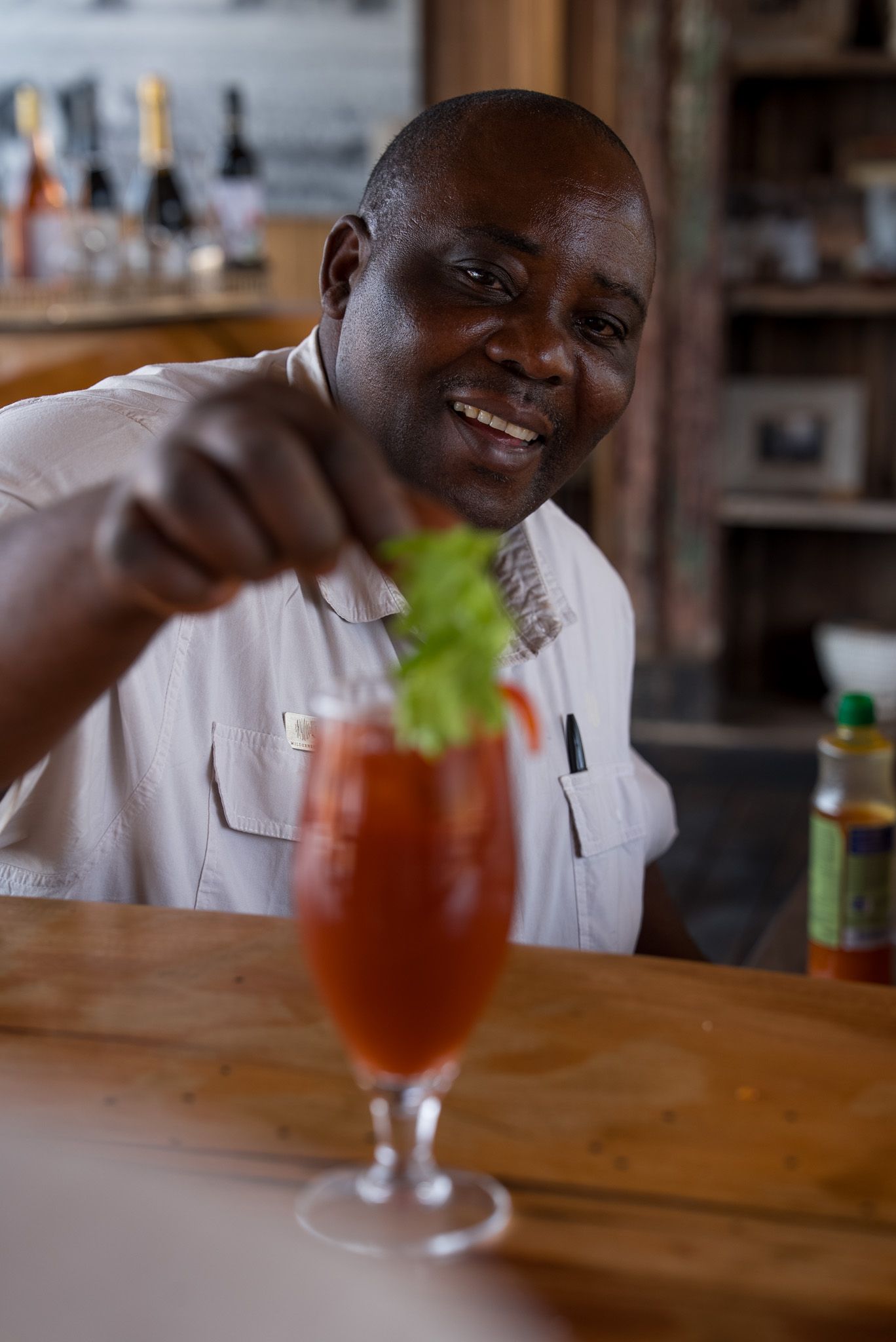 Bartender garnishing a refreshing red cocktail at a wooden bar counter.