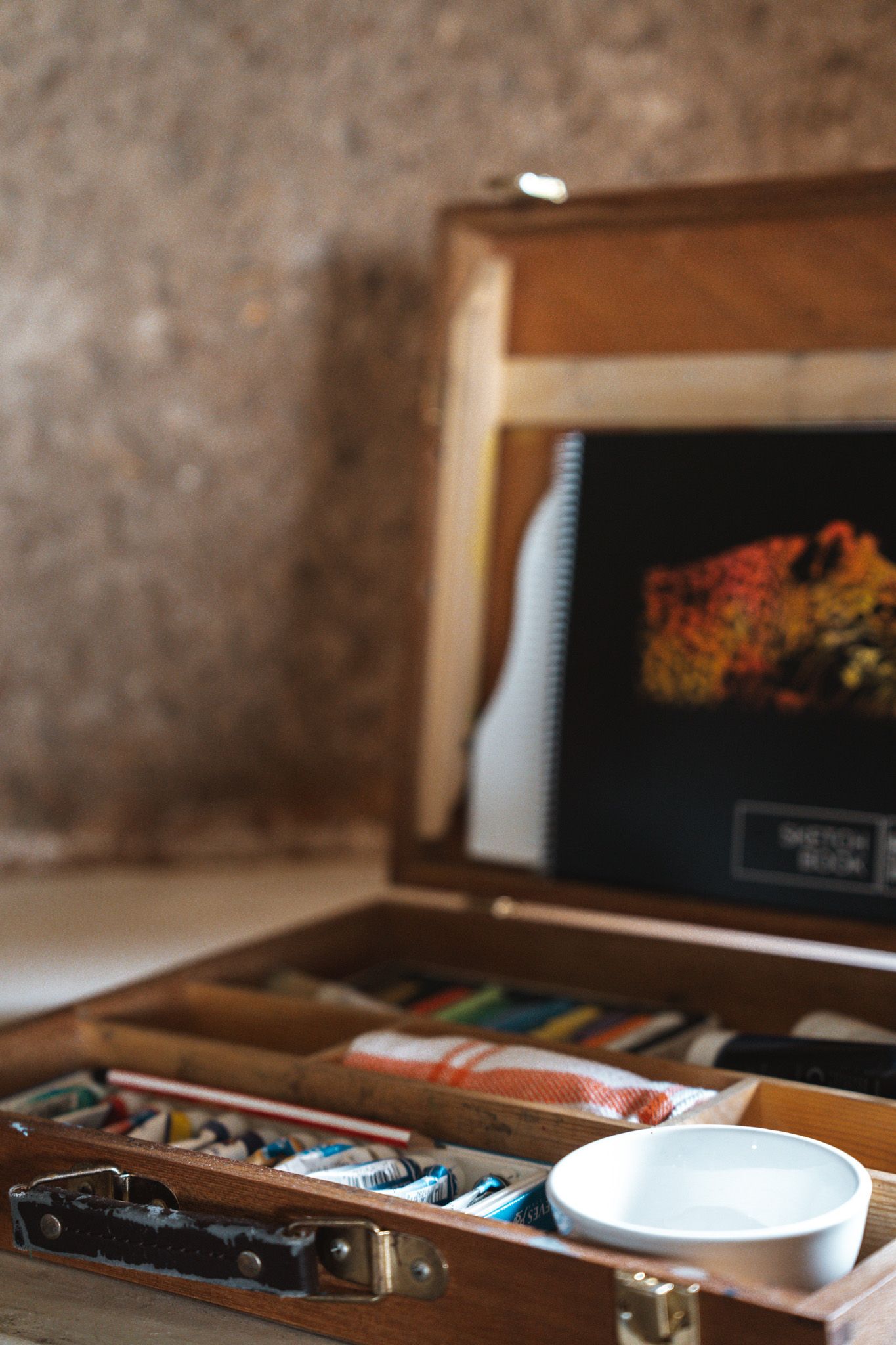 Organized drawer containing art supplies and crafting materials in wooden compartments.
