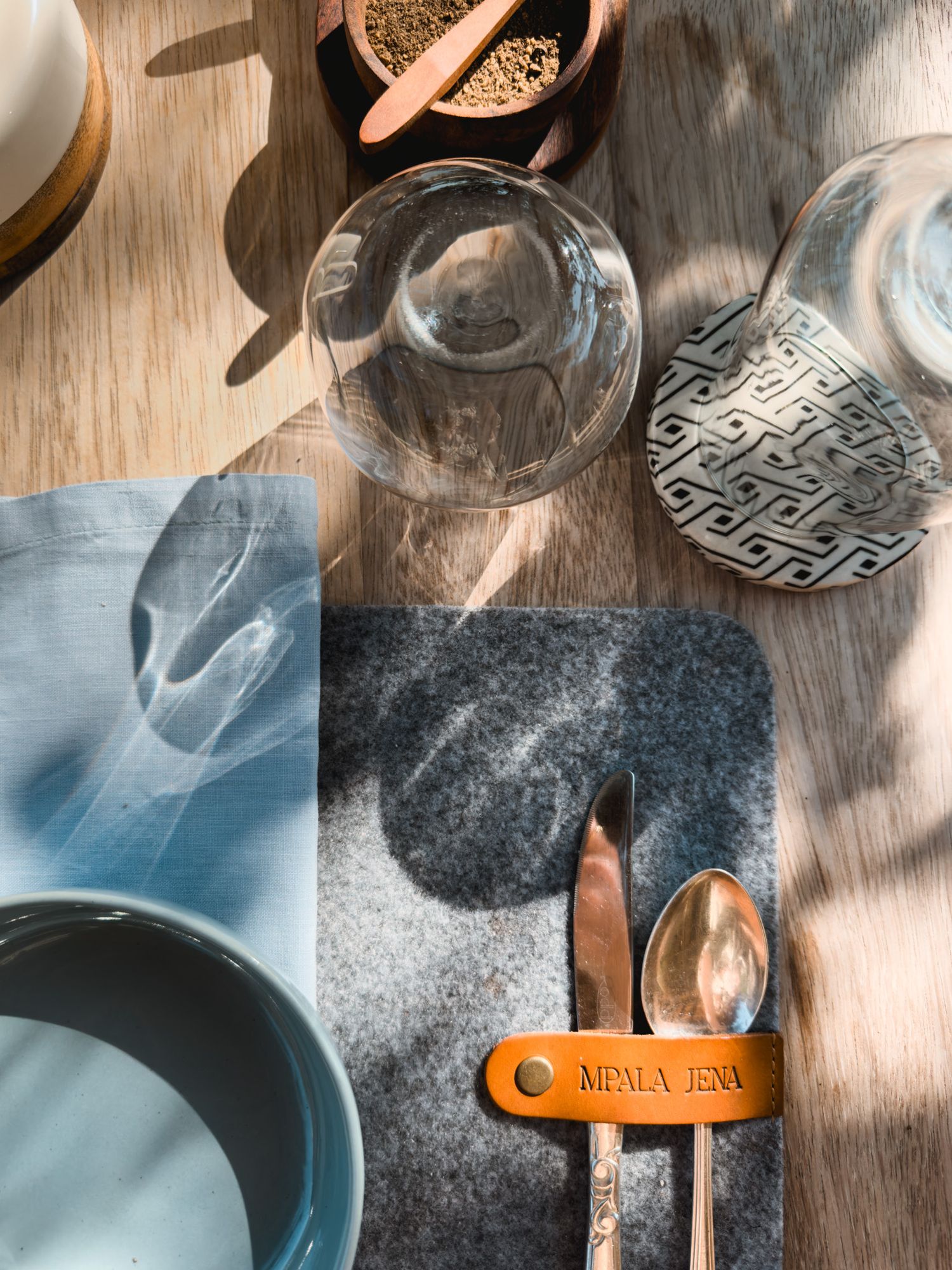 Overhead view of kitchen items including glassware, utensils, and dining accessories on wooden surface.