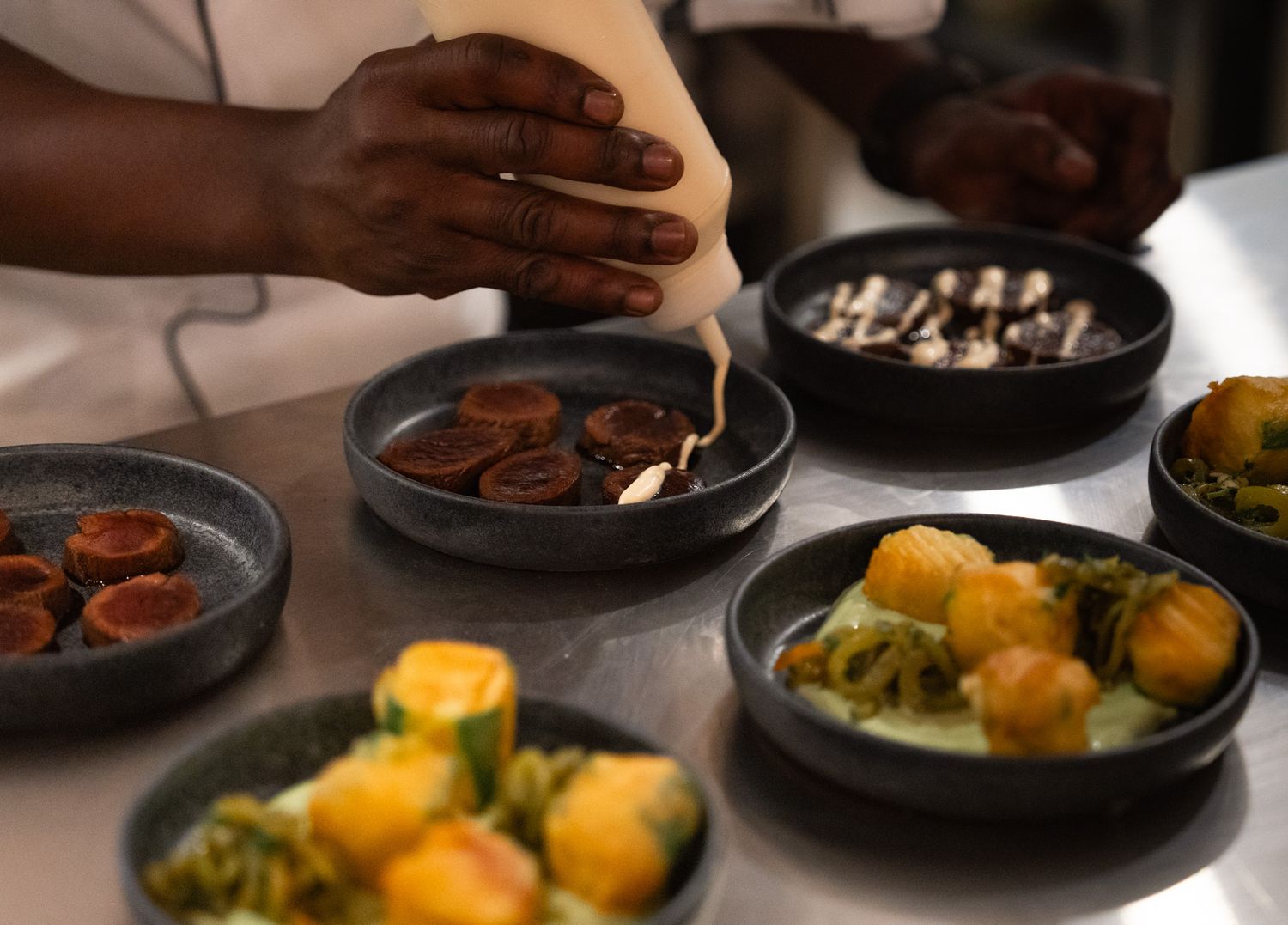 Various colorful dishes being served in cast iron skillets on dark surface.