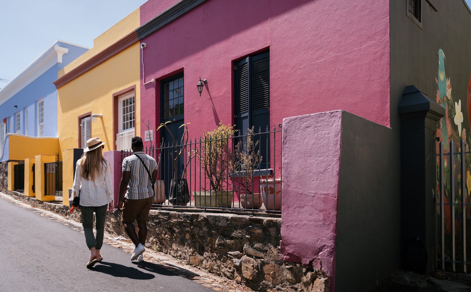 Colorful Mexican street scene featuring buildings painted in vibrant pink, blue, and yellow with traditional colonial architecture.