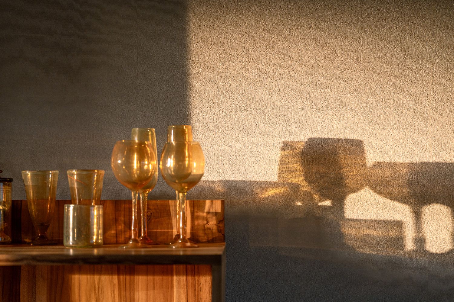 Amber glassware collection on wooden surface catching afternoon sunlight.