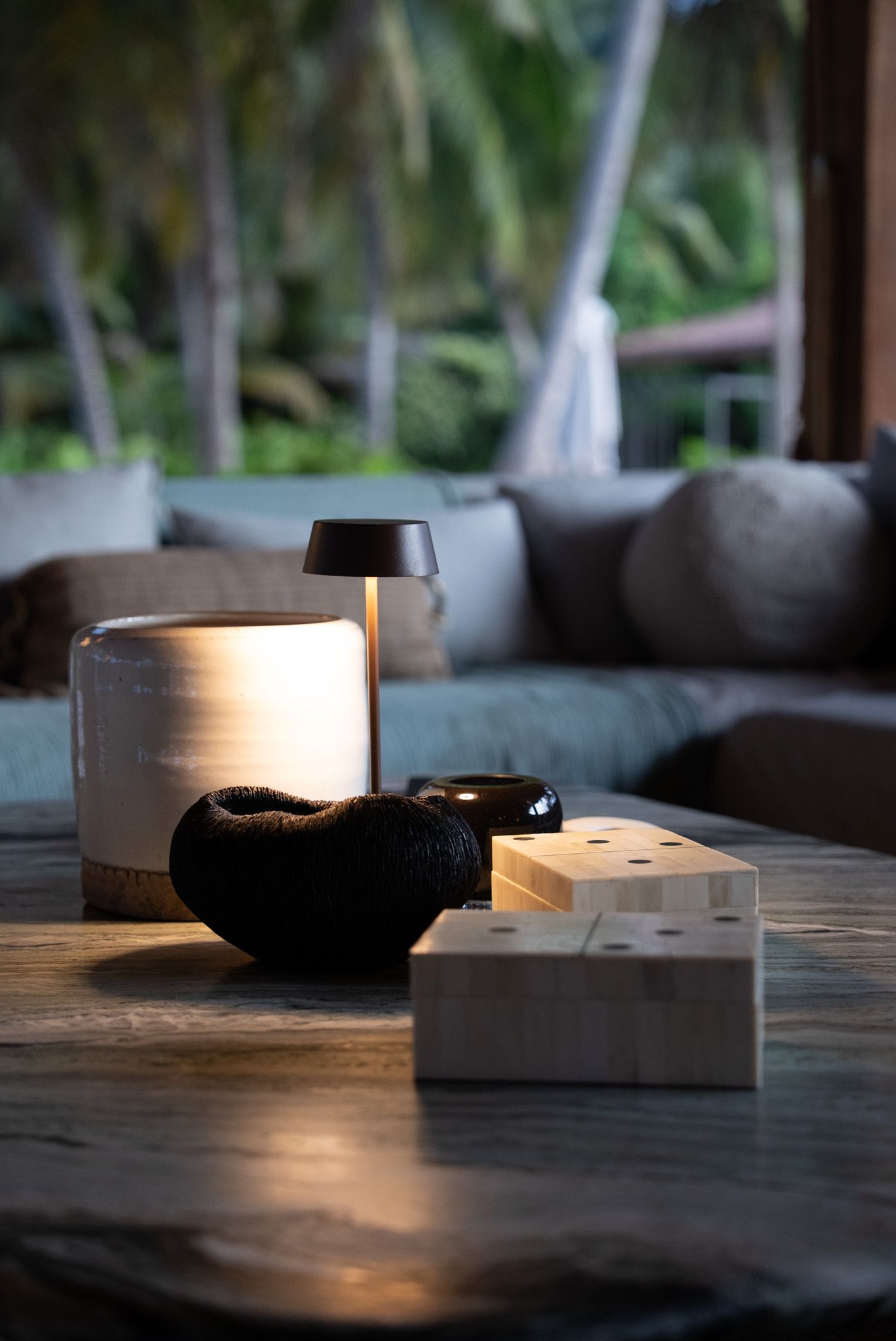 Black ceramic tea bowls and wooden serving board on rustic table with dramatic lighting.