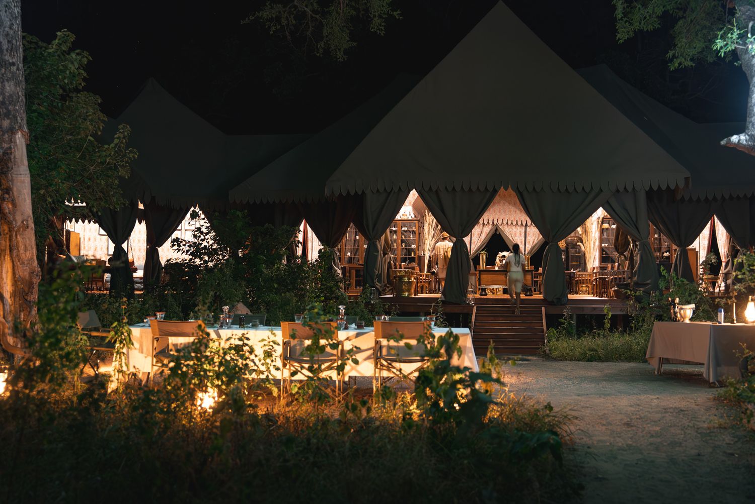 Illuminated luxury safari tents arranged in a row at night creating a romantic glamping atmosphere.