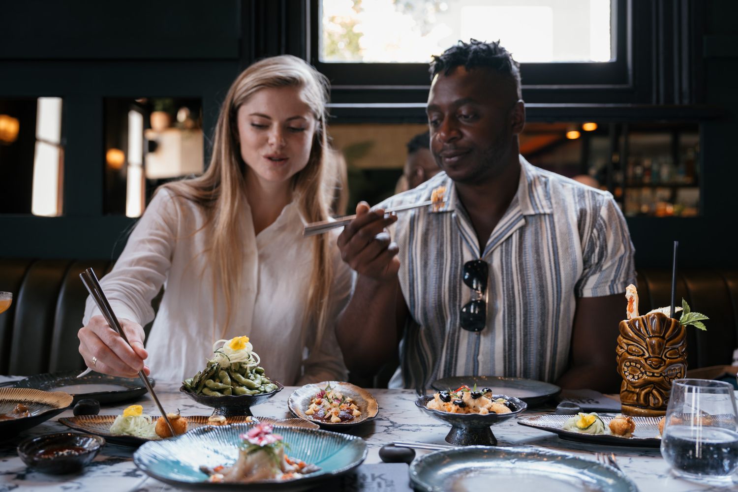 Casual dining scene with plates of food and drinks on dark restaurant table.