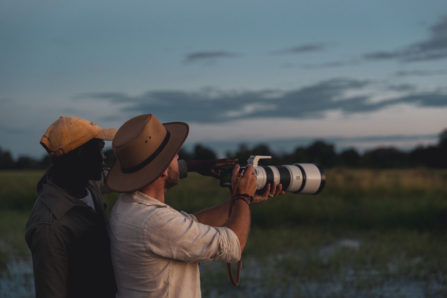 Two photographers with long lens cameras shooting wildlife at sunset.