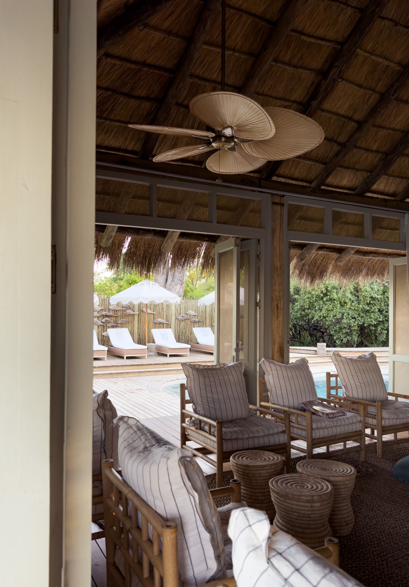Tropical-style covered patio with palm leaf ceiling fan and comfortable outdoor seating.