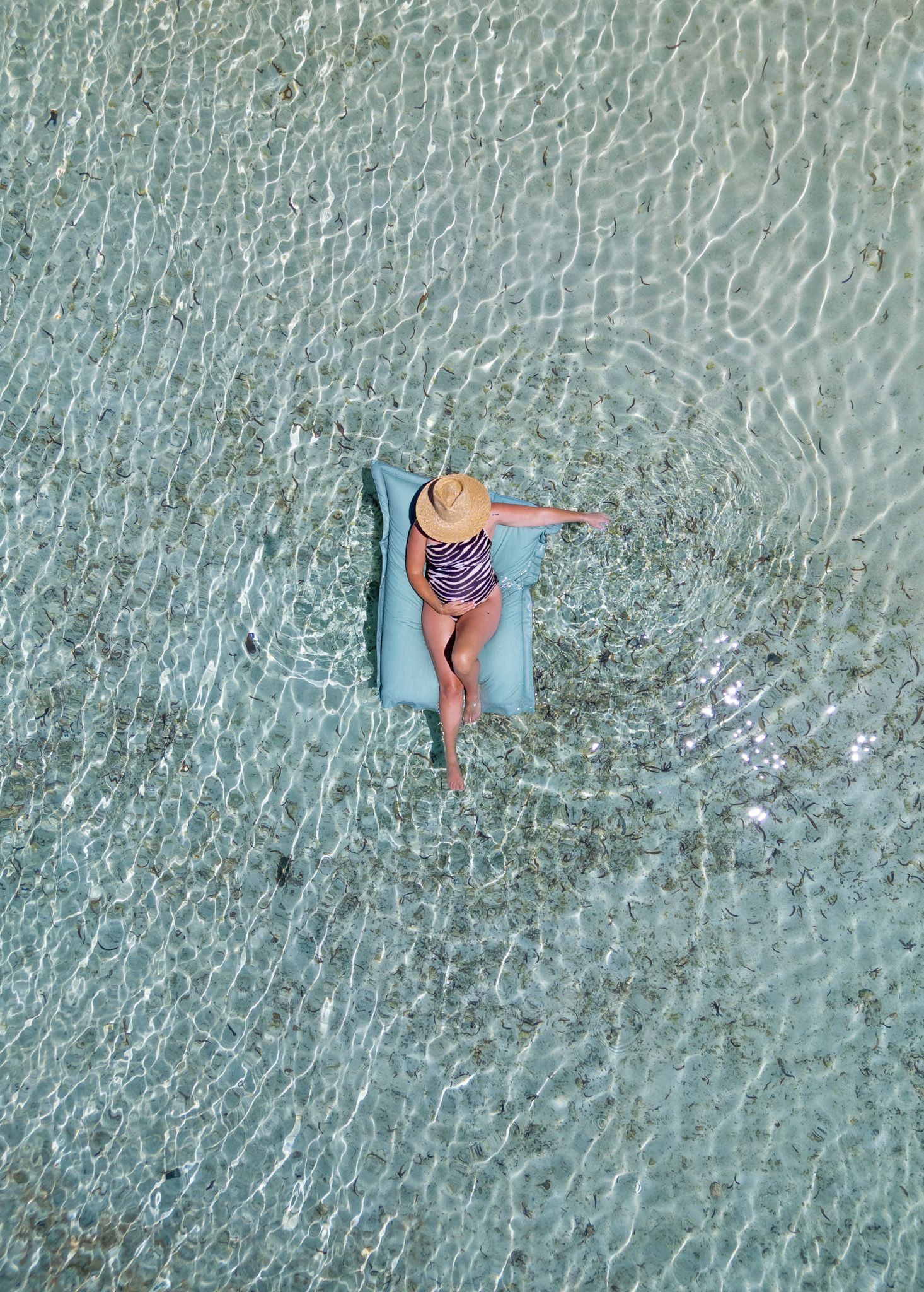 Aerial view of swimmers floating in crystal clear turquoise ocean waters.