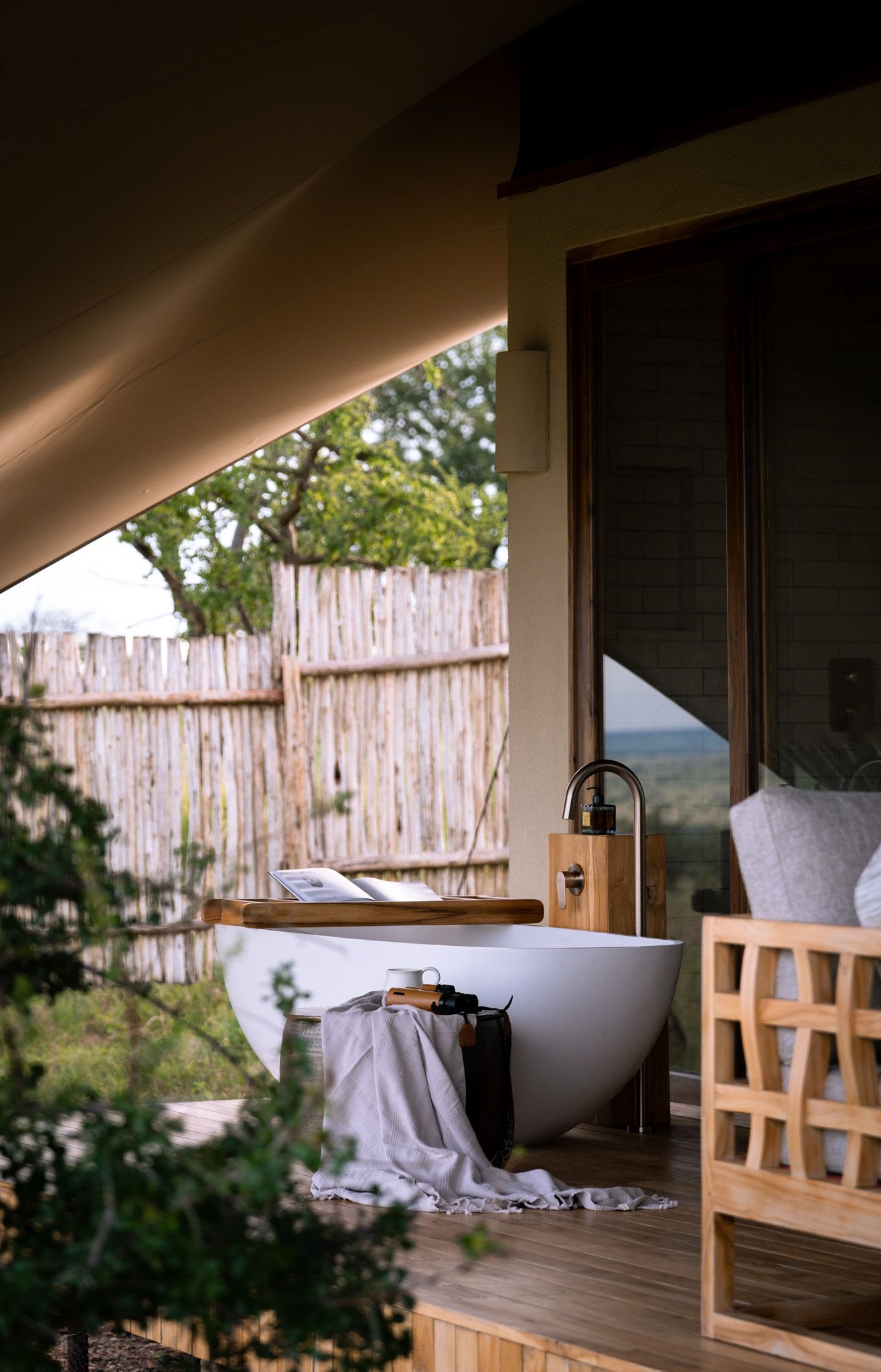 Luxurious outdoor bathtub on wooden deck with privacy fence and natural surroundings.