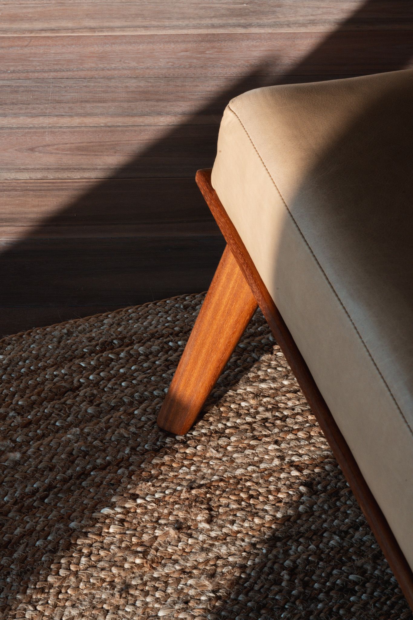 Close-up of modern beige upholstered furniture with wooden leg detail on textured carpet.