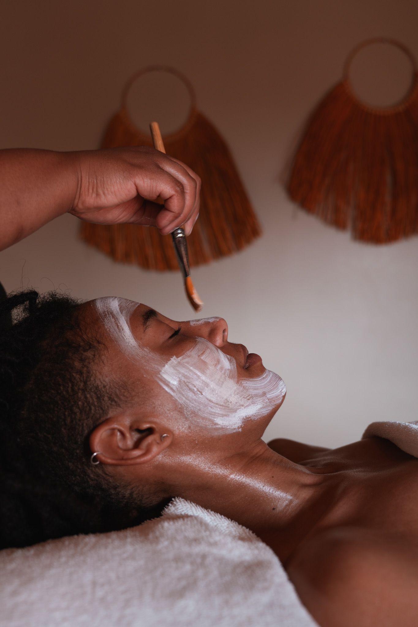 A relaxing spa treatment showing a person receiving a facial mask application in a serene setting.