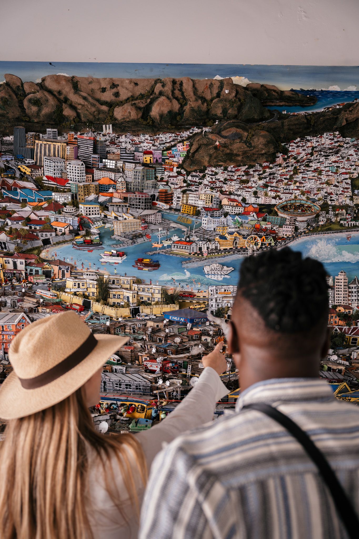 Panoramic cityscape view of a coastal town with colorful buildings nestled among rocky terrain.