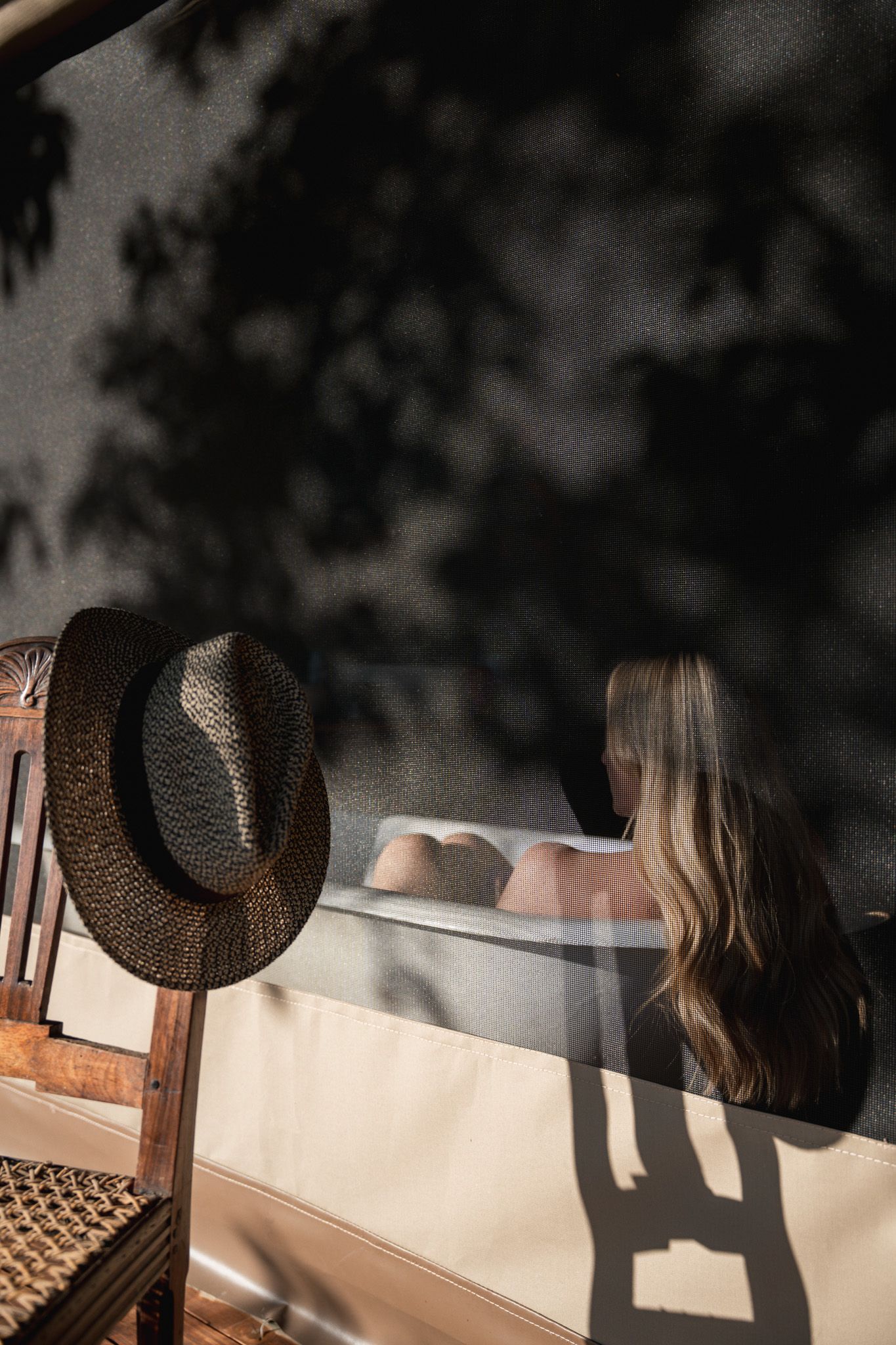 Artistic shadow play with a straw hat and figure in soft natural lighting.
