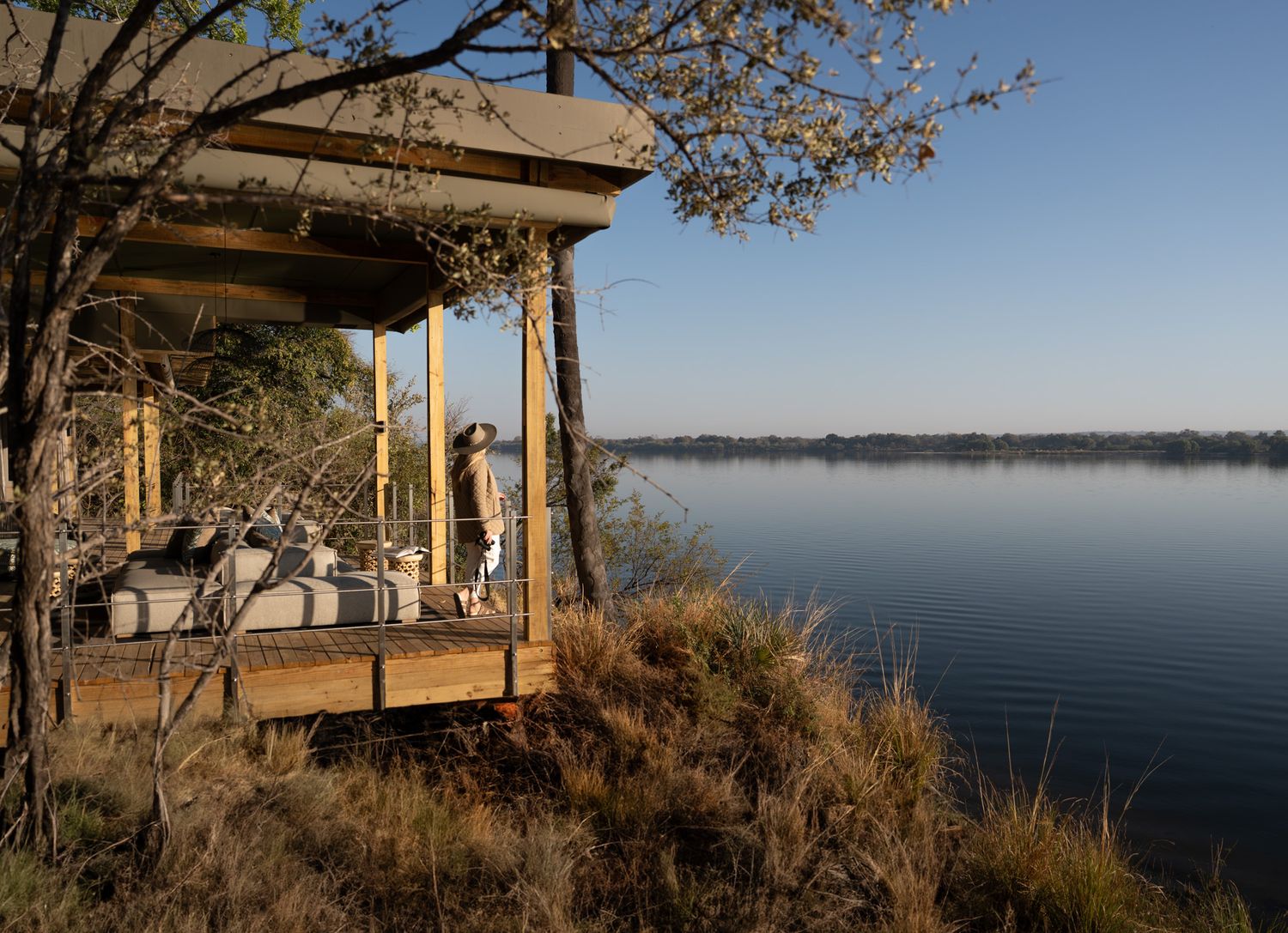 Wooden deck pavilion perched on a hillside overlooking a serene lake.