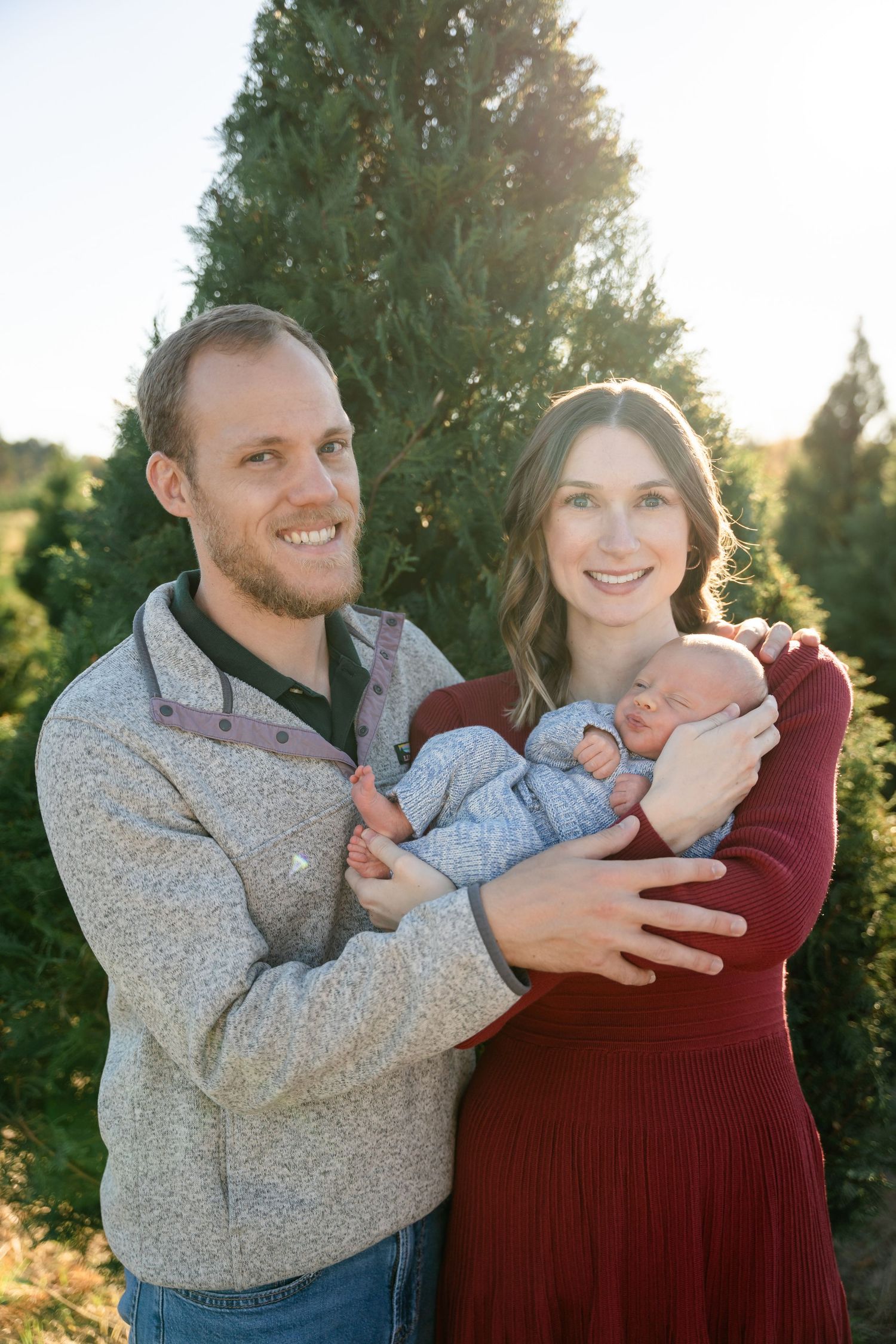 Couple embraces during sunset photoshoot with evergreen trees in background.