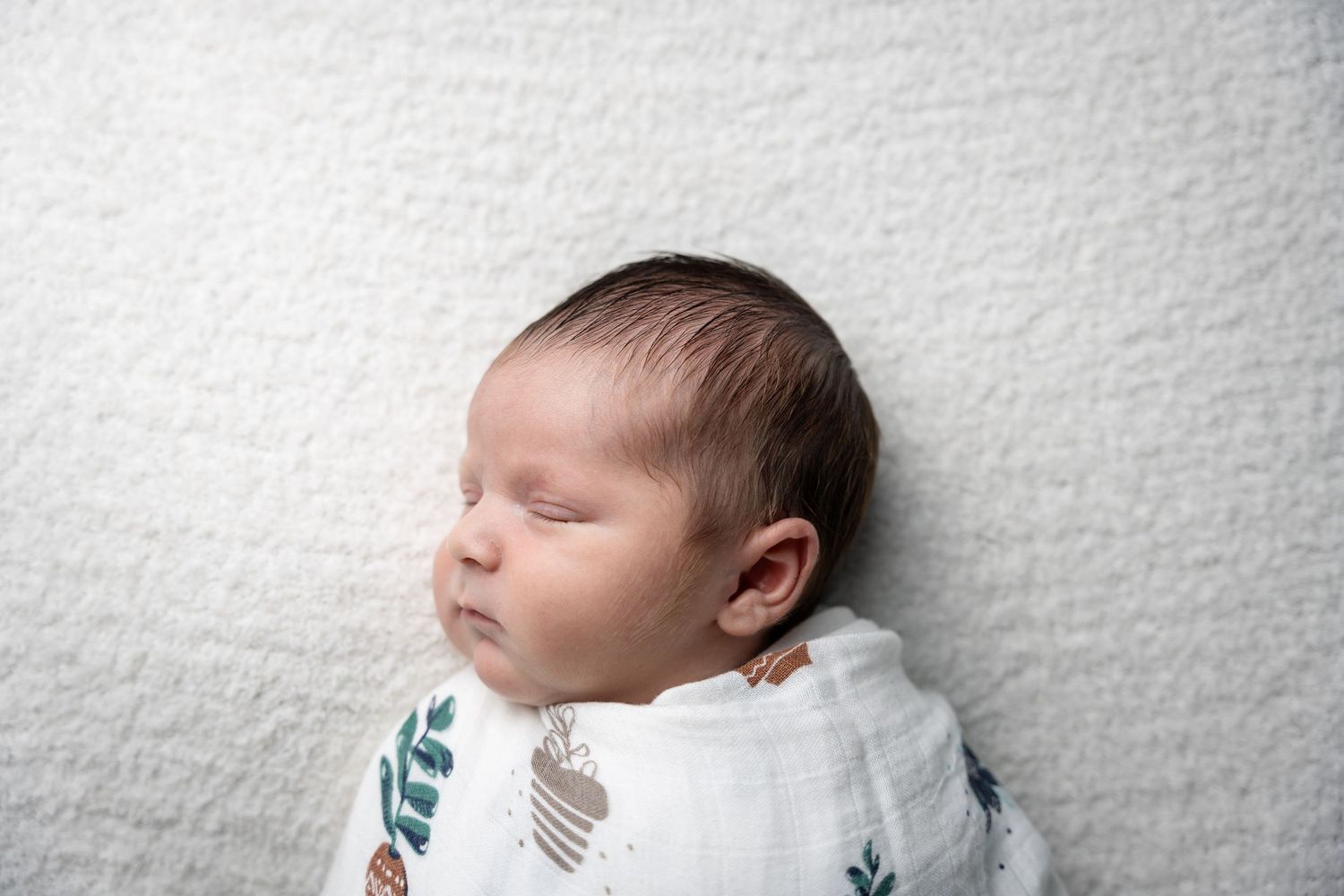 Professional newborn photography on soft white textured blanket.