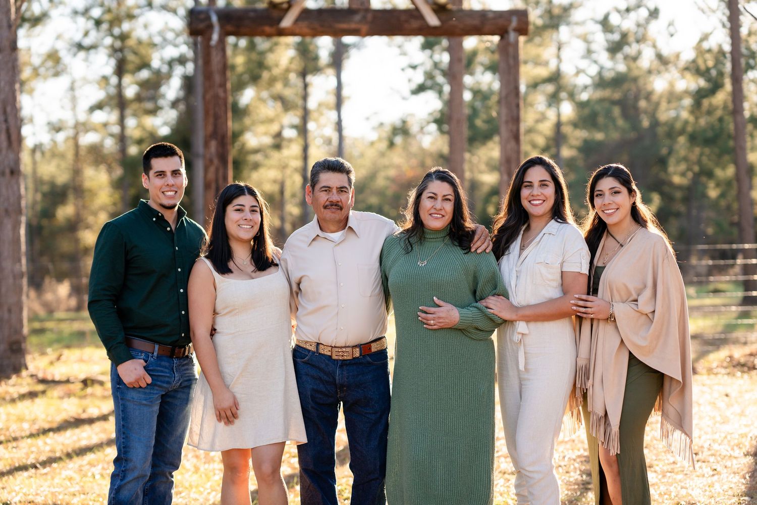 A group wearing coordinated outfits stands together against a backdrop of tall pine trees.