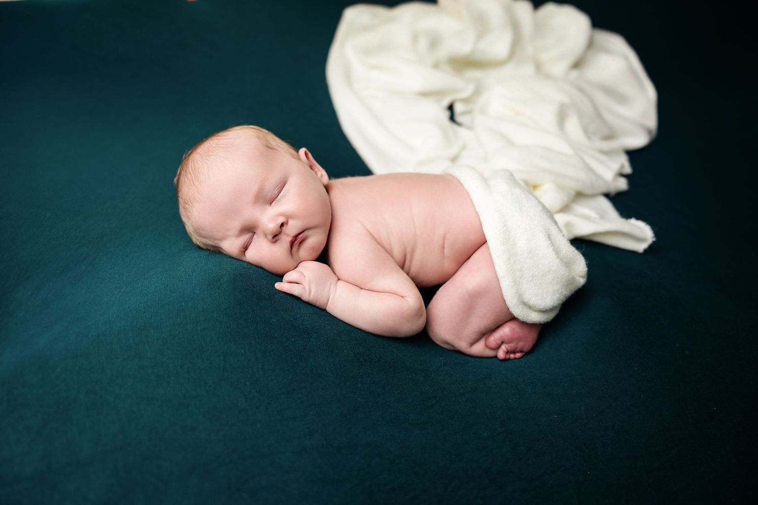 Artistic black and white portrait of sleeping newborn with white fabric.