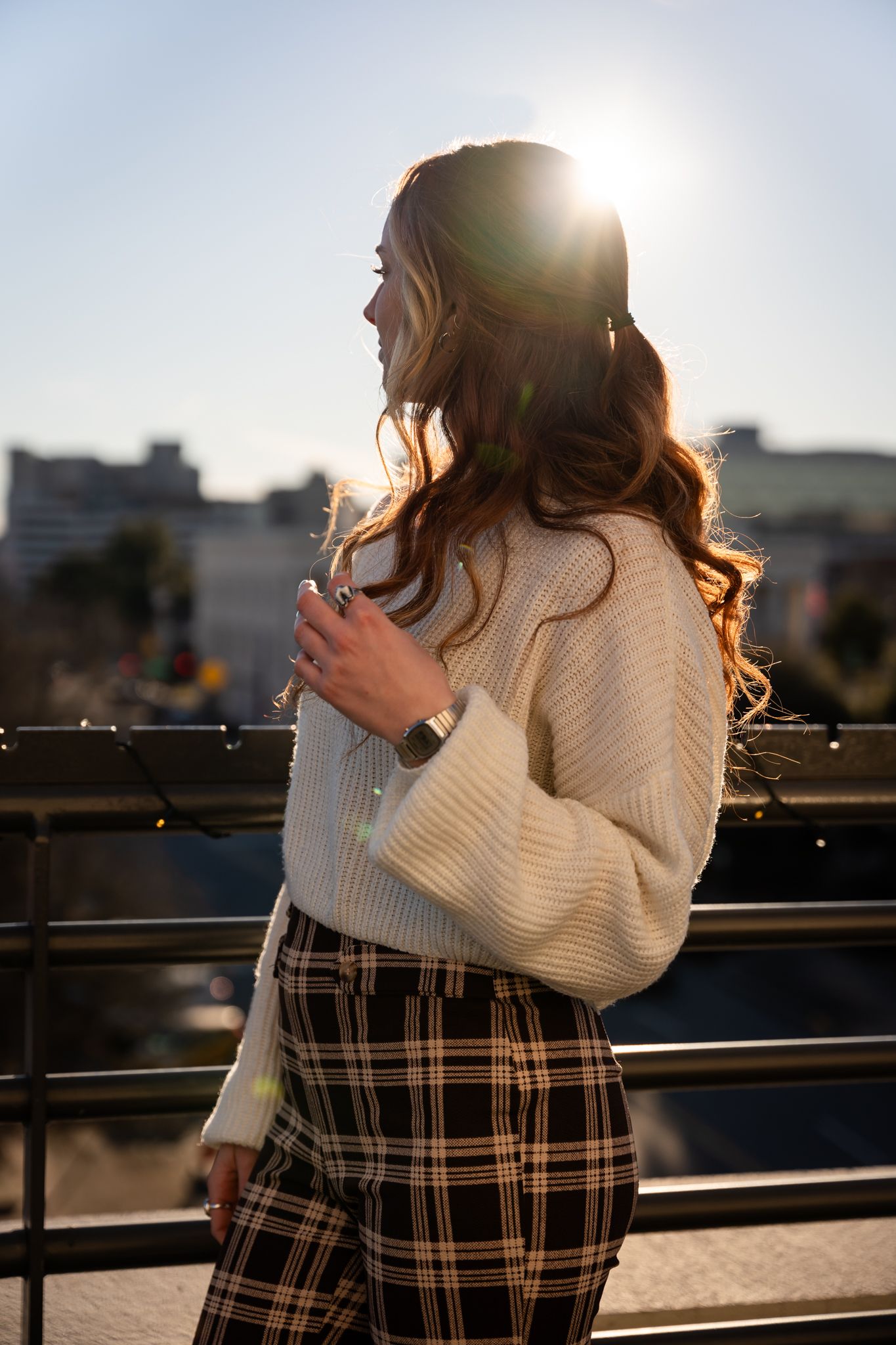 Backlit silhouette on rooftop showing person in knit sweater and plaid pants during golden hour.