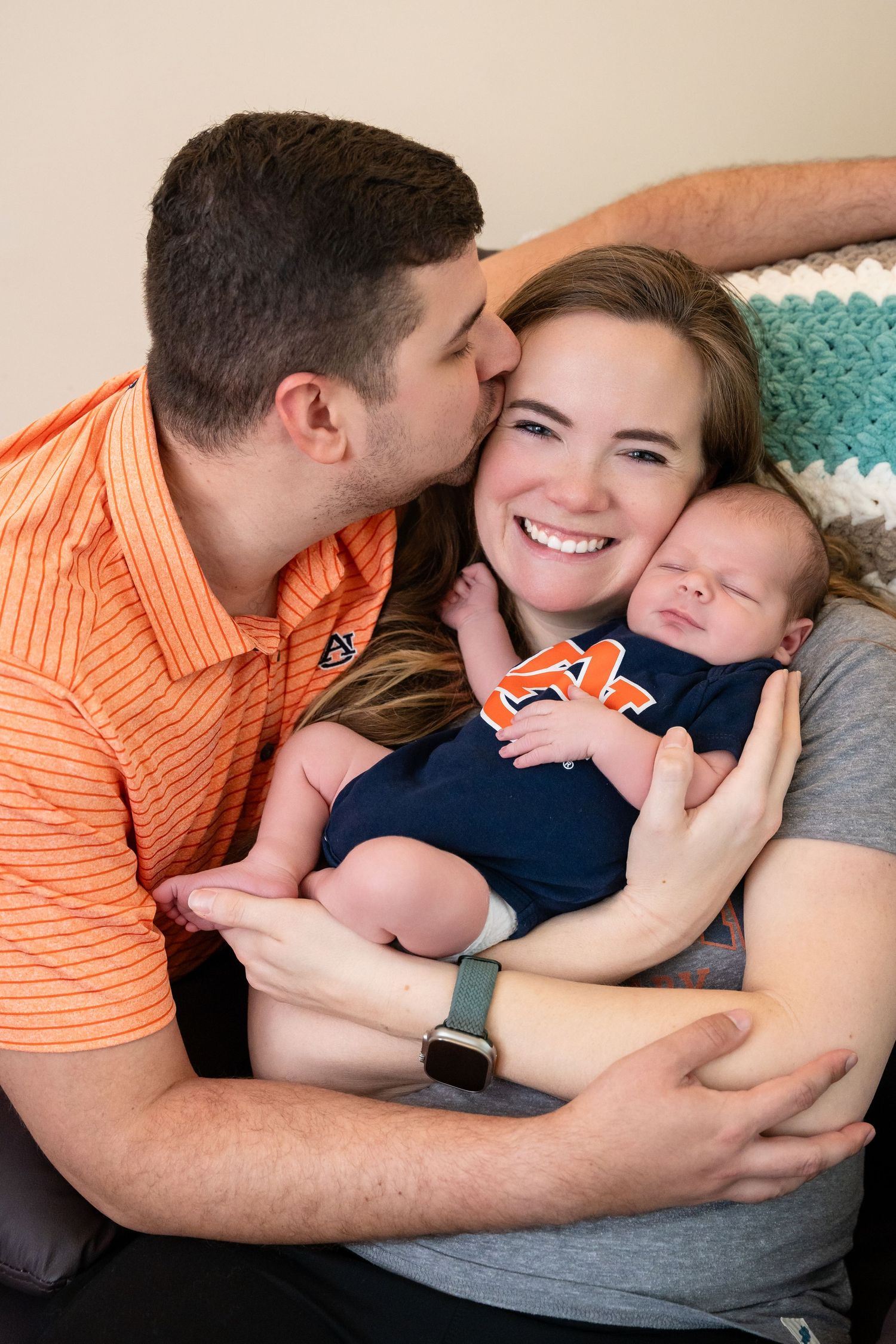 Loving family moment with baby in Auburn University apparel.