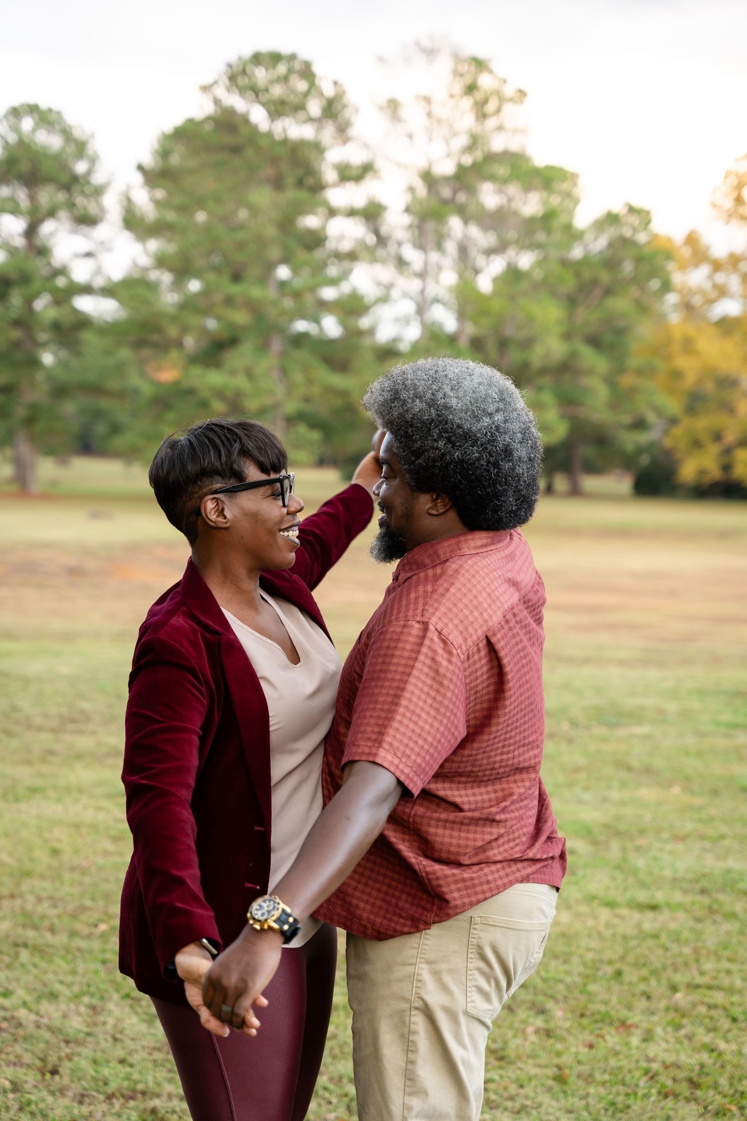 Two people share an energetic interaction while wearing coordinated burgundy outfits in a field.