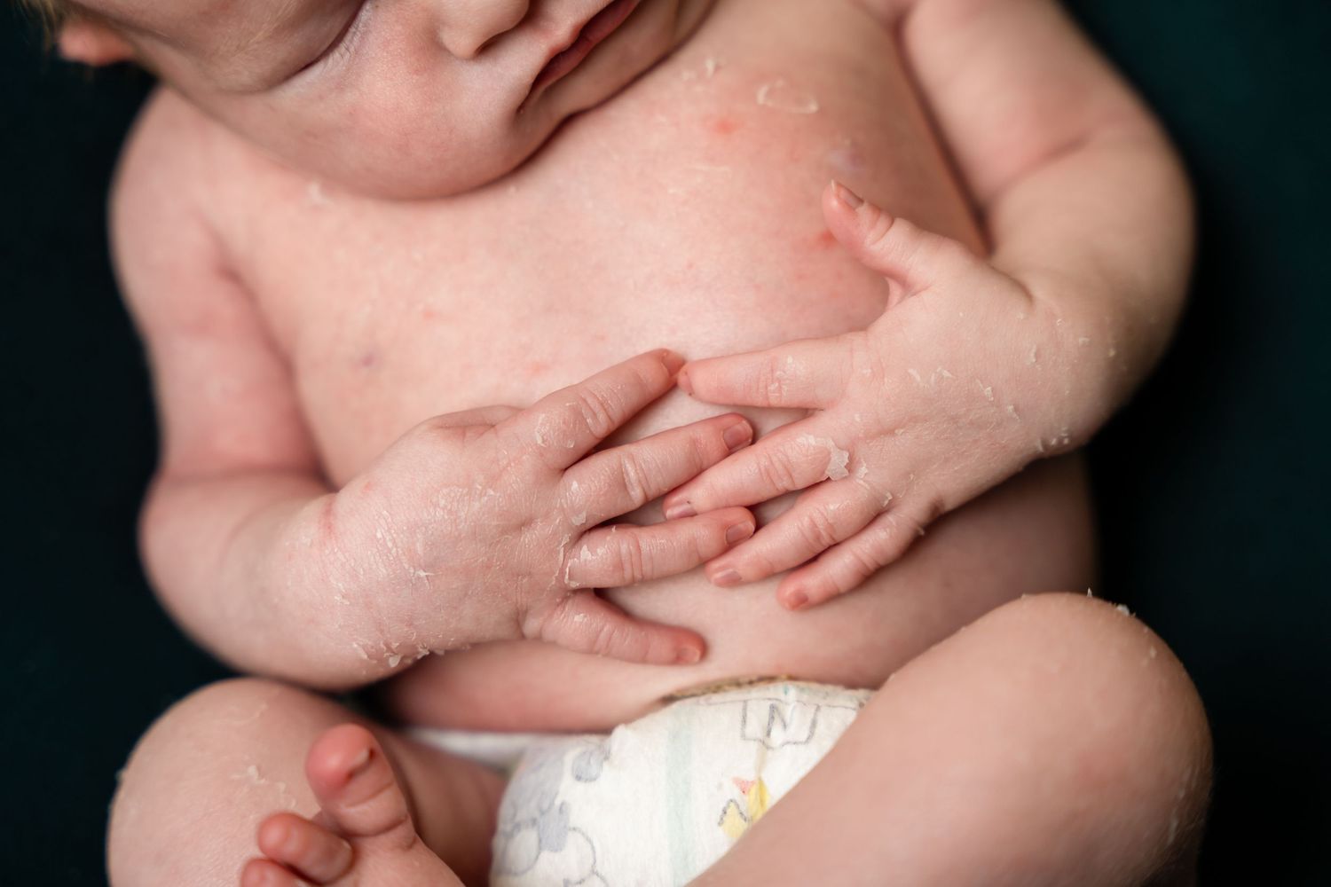Close-up details of newborn baby against dark background in artistic style.