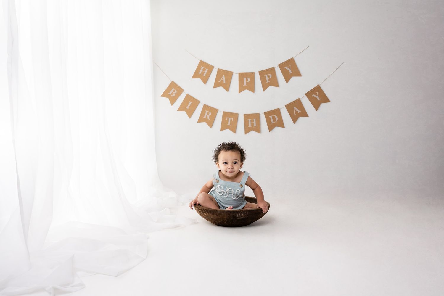 Minimalist white photo setup with kraft paper banner hanging above.