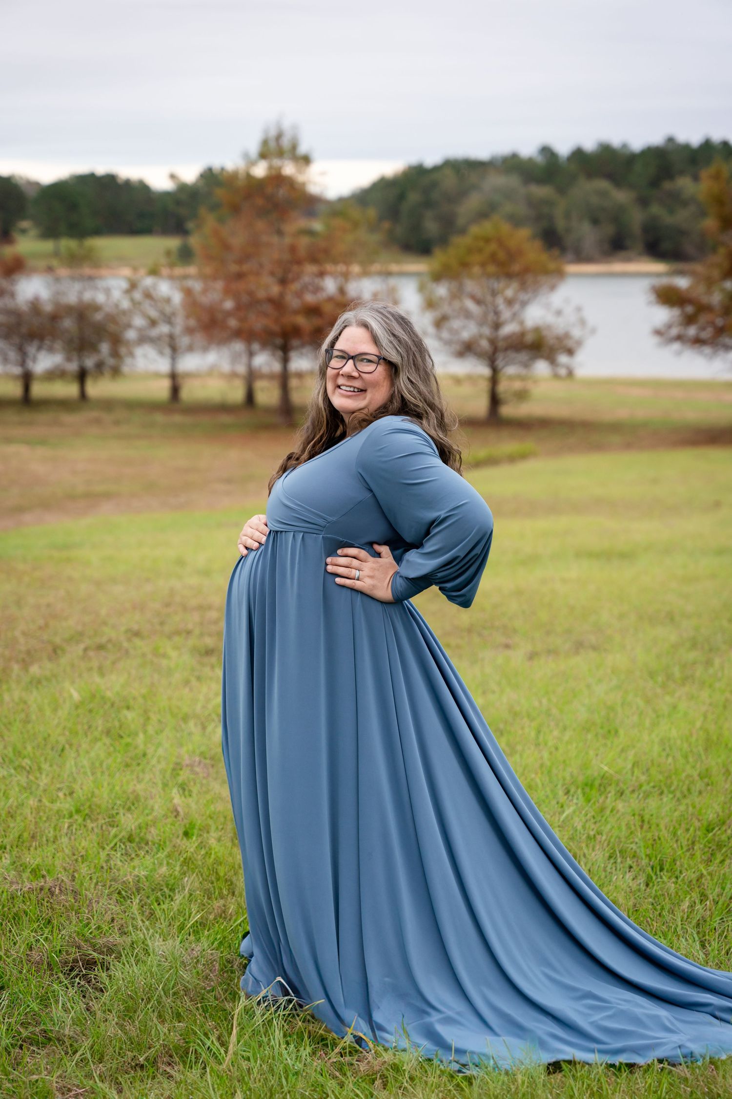 Flowing blue dress creates dramatic movement in outdoor maternity photos.