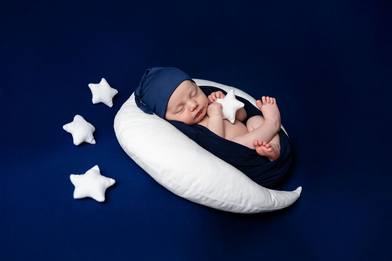A collection of navy blue themed newborn photography shots with moon and star decorative elements.