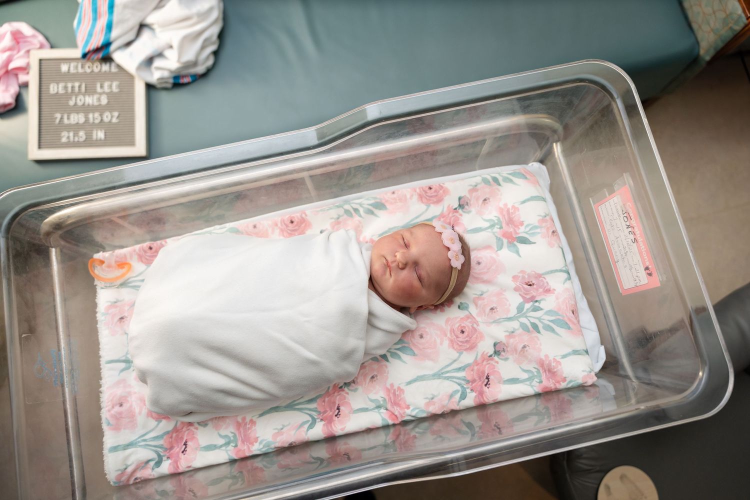 A lifestyle newborn photography session showing baby resting on floral bedding.