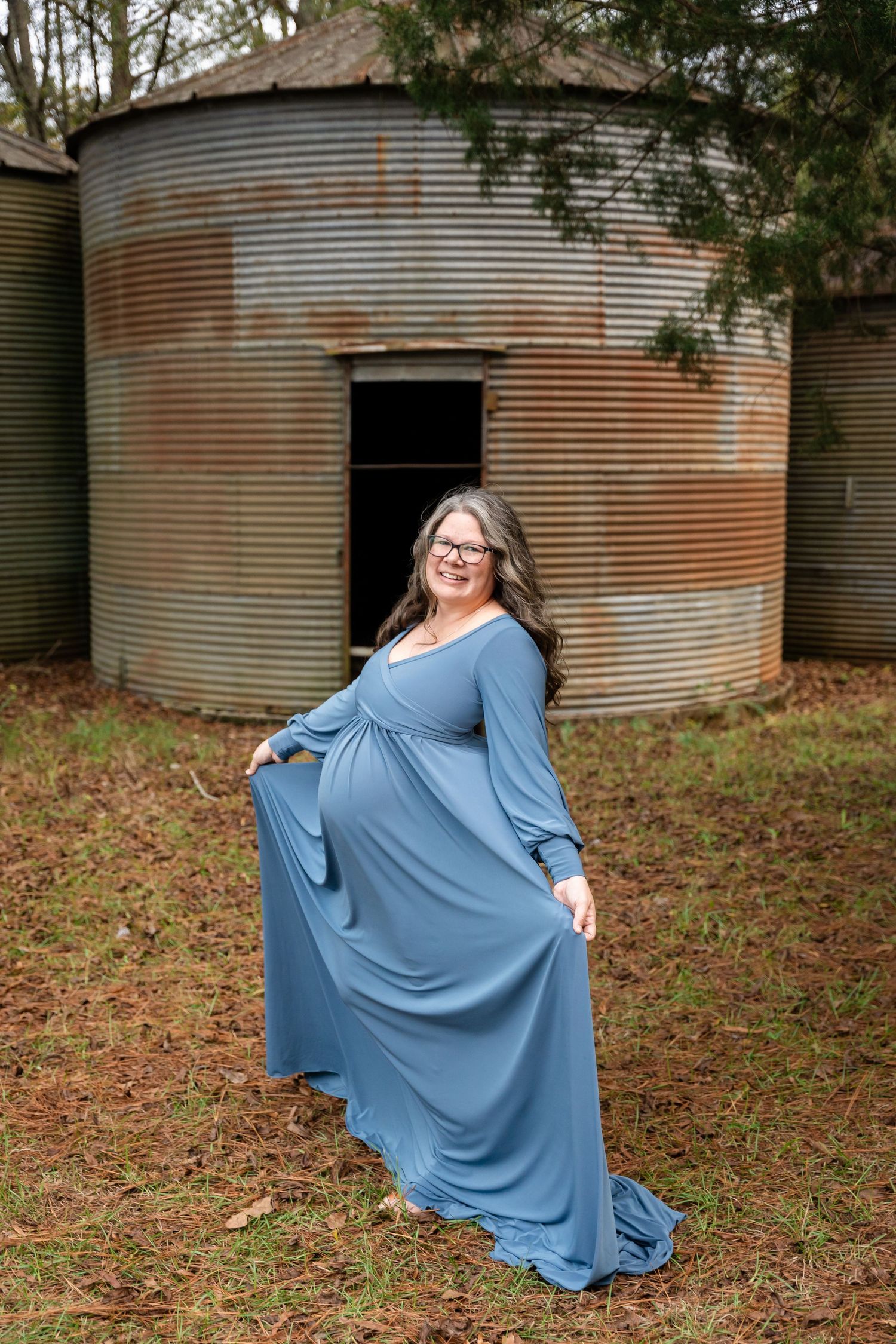 A flowing blue dress twirls against a backdrop of metal grain storage bins.