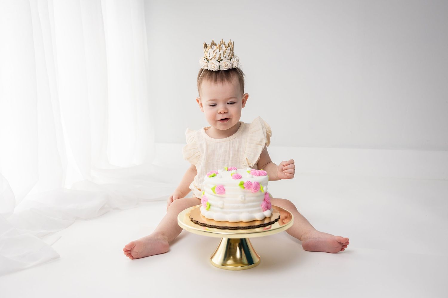 A cake smash photo session showing progression of a small child with a decorated birthday cake against white backdrop.