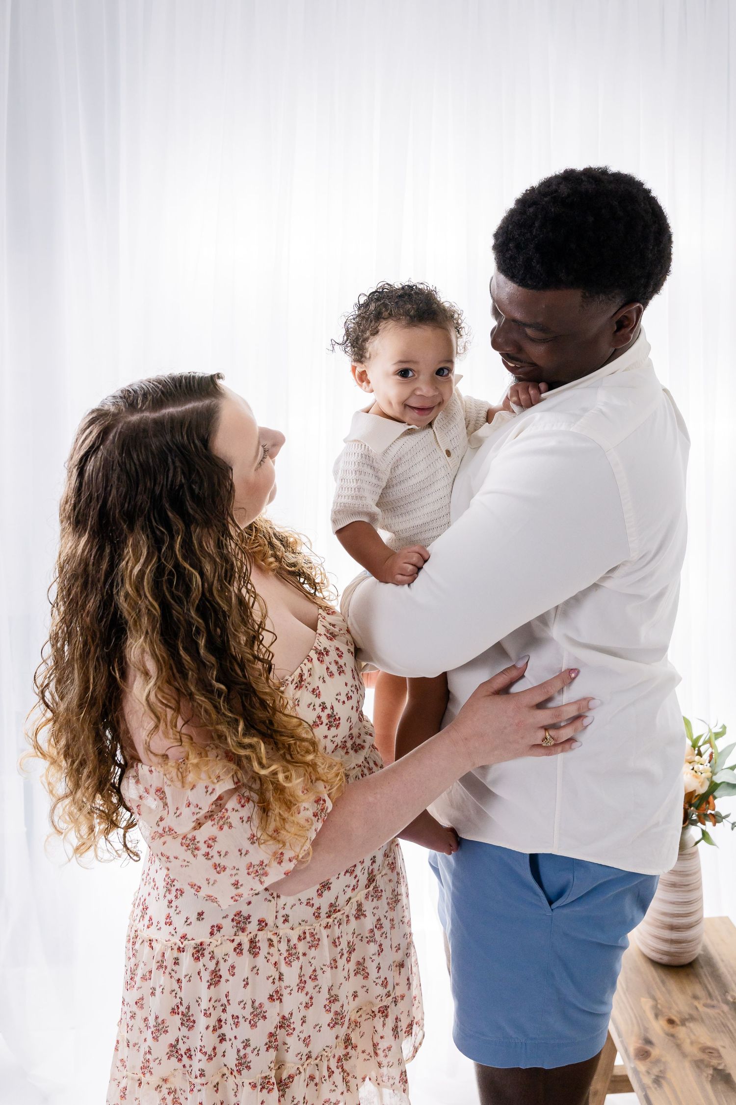 Candid family portrait session showing loving interactions against white backdrop.