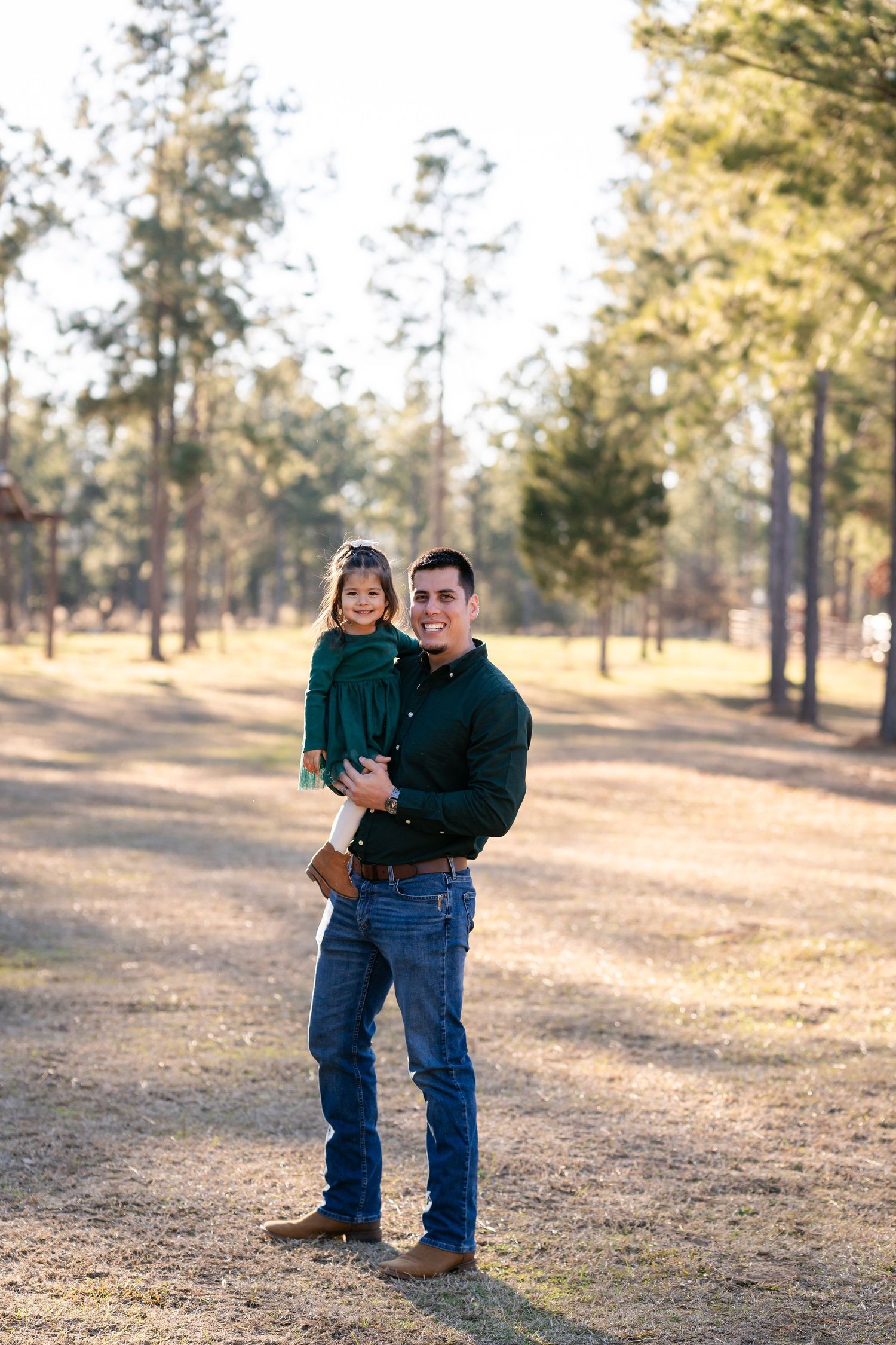 A playful outdoor photoshoot between family members in casual attire during golden hour.