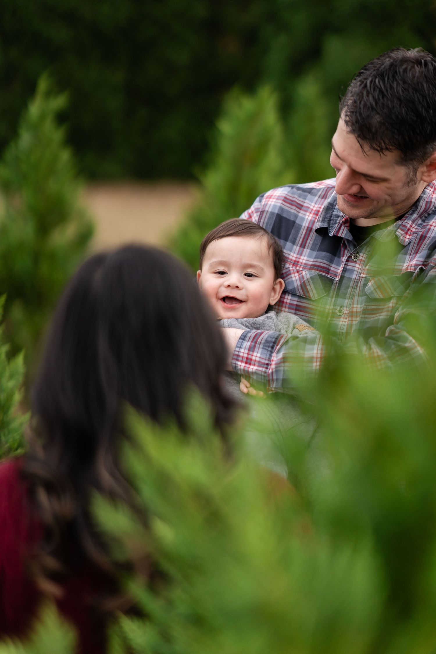 Candid moments of joy shared between family members at a tree farm.