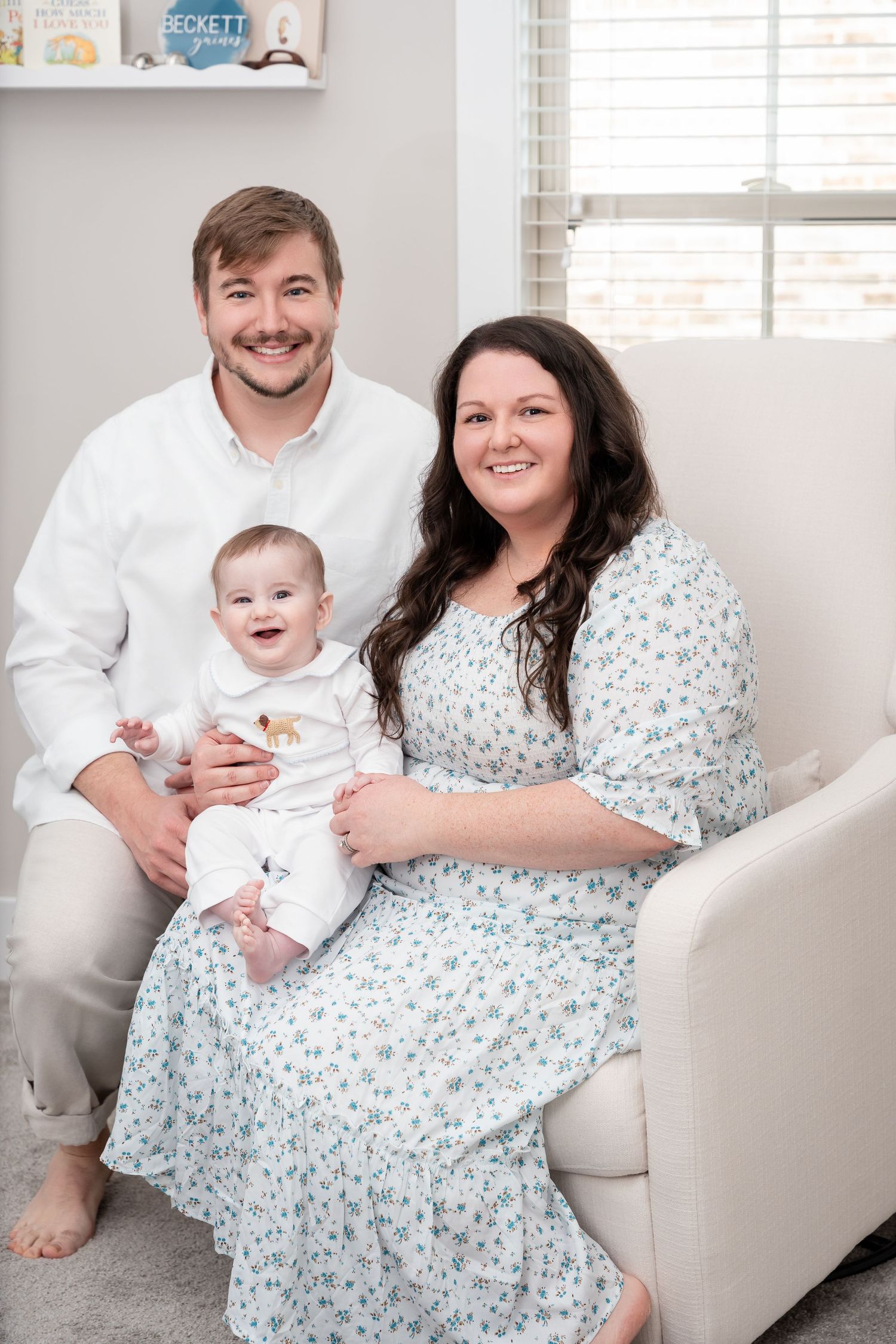 A family portrait in a cozy living room with neutral decor and natural lighting.