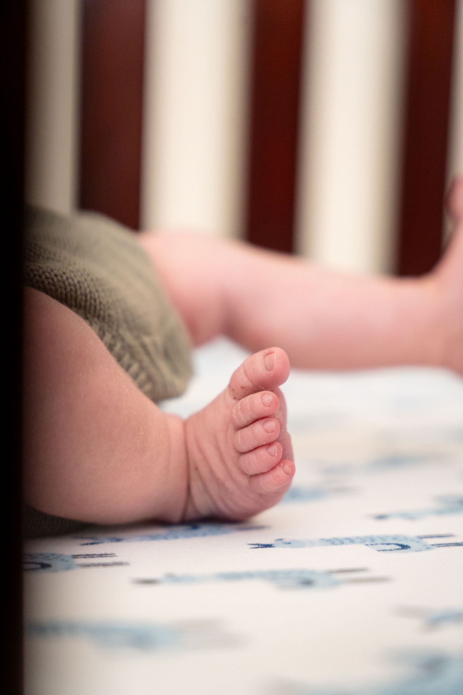 Close-up view of tiny baby feet against white bedding with blue details.